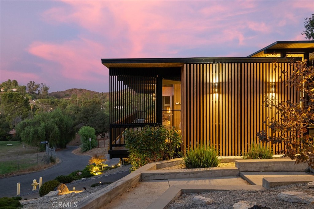 A Rare Mid-Century Modern Gem with Iconic Design and Panoramic Views
Mid-century modern homes of this caliber rarely come to market. Designed by architect Dale Bergerson with legendary A. Quincy Jones. built in 1965 for the Zimmerman family, this architectural treasure embodies the clean lines, open spaces, and indoor-outdoor flow that define the era.
Perched on a knoll above the 15th green of the Woodland Hills Country Club, the home captures sweeping mountain and golf course views through walls of glass and clerestory windows. Natural light floods the interior, highlighting Venetian plaster walls and distinctive tile and white oak flooring. Post and Beam construction creates a timeless, airy ambiance.
The living space is centered around a dramatic gas fireplace and seamlessly connects to both front and rear outdoor areas. A Teak wood entertainer’s deck spans the back of the home, featuring a Viking outdoor kitchen, built-in spa, and tranquil custom waterfall, all framed by a towering wall of timber bamboo for added privacy.
The chef’s kitchen is fully outfitted with premium appliances, including a Wolf range, Sub-Zero glass refrigerator, Miele built-in coffee station, and a temperature-controlled wine cooler. Three spacious bedrooms and two bathrooms are intelligently placed along a wide, open floor plan. The primary suite opens directly to the front deck, offering morning sunlight and evening serenity.
The landscaping is a masterclass in balance and simplicity, inspired by traditional Japanese garden design. Additionally, a newly remodeled bonus room below the main residence offers flexible use—currently serving as a home theatre and art studio.
Thoughtfully designed and impeccably maintained, this home is a rare opportunity to own a piece of architectural history with all the luxuries of modern living.
*PROFESSIONAL PHOTOGRAPHY COMING SOON.
