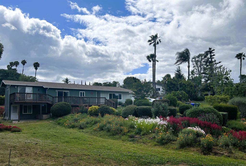 Tucked away in the heart of Fallbrook, this charming home sits on just over half an acre surrounded by colorful, blooming gardens. Inside, freshly painted interiors and new flooring in several areas create a warm, welcoming feel. The versatile layout includes 3 bedrooms plus 2 bonus rooms, perfect for an office, creative space, or even a potential ADU with its private entrance. A cozy fireplace anchors the family room, adding both charm and comfort. The primary suite features dual closets, an en-suite bath, and direct access to the expansive deck, an ideal spot to unwind and take in stunning western sunsets. Just a few touches needed to bring your vision to life in a truly special setting. The backyard offers privacy, covered patios, and garden beds ready for your personal touch. Recent upgrades bring peace of mind, including a newer roof, windows, sliders, house fan, insulation, dishwasher, and water heater. Just minutes from the new Village View County Park, schools, shopping, and downtown Fallbrook, this home blends comfort, potential, and convenience.