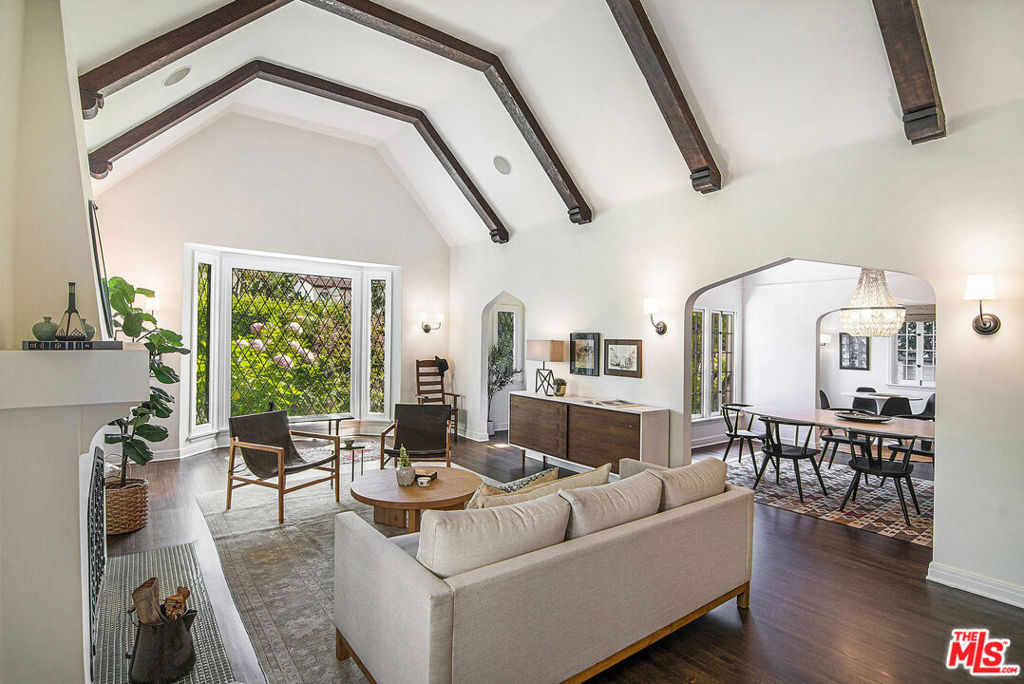 STUNNING AND ULTRA-PRIVATE TUDOR HOME IN BEVERLY GROVE. Enter this incredible home through a fully hedged, enclosed front yard, foyer entryway into an expansive living room with vaulted, beamed ceiling, picture window and fireplace. The living room opens to a formal dining and remodeled kitchen with a breakfast room/family nook, marble counters, Viking stove and adjacent laundry room. There are three generous bedrooms including a primary suite with marble spa bath with soaking tub, walk-in closet and French doors leading to a trellised rear patio, outdoor dining area, and finished garage/flexible space with full bath. Additional features include central AC, coved ceilings, recessed lighting, sound and alarm system, powder room, beautiful period details, ample storage and closet space, side patio, ideal situated mid-block. This gorgeous home is a rare find in a highly coveted location.