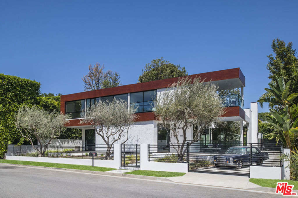 This modern newly constructed residence, designed by Gabbay Architects, sits discreetly behind mature olive trees on one of Beverly Hills' most sophisticated streets. Spanning three stories, the home is centered around a meticulously crafted wooden staircase, winding elegantly against a glass-enclosed atrium. Stone walls, soaring ceilings, exquisite herringbone wooden flooring, and expansive floor-to-ceiling glass panels adorn the main level, seamlessly connecting indoor and outdoor spaces. Boasting five bedrooms and seven baths, the home offers opulent living spaces with refined proportions. The stylish family room flows into a chef's kitchen featuring dual sinks, a spacious island, and a cozy breakfast nook, all overlooking the rear terrace, built-in kitchen/dining area, pool, and lushly landscaped yard. The lower level hosts a theater room, a well-appointed bar and lounge, an office/guest bedroom, and a stunning 15-car garage with ample storage, as well as an additional bedroom and bathroom. Upstairs, four bedrooms and an open lounge/loft with a balcony provide a versatile space, ideal for a media room or play area. The primary suite offers dual walk-in closets, a luxurious spa-like bath with a soaking tub, and elegant stone accents. Conveniently located near Sunset Boulevard, the Beverly Hills Hotel, Rodeo Drive, as well as an array of shops, restaurants, bars, and parks, this home epitomizes the sophisticated lifestyle of Southern California.