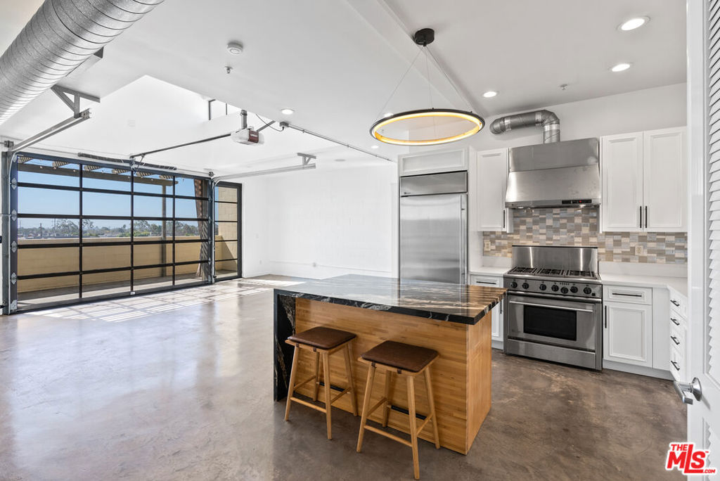 Designed by award-winning architects Pugh + Scarpa, the 12th Street Lofts are among the most coveted boutique residences on the Westside. With only 12 units in the entire building, exclusivity is built into the DNA of this address. Perched on the top floor and facing south, Residence 303 is flooded with natural light from morning to evening. Loft-style volume, polished concrete floors, and soaring ceilings create an open canvas for modern living. The living area extends seamlessly to a private terrace through a dramatic roll-up glass door, a design element that transforms the space with a single touch. The chef's kitchen features custom cabinetry and premium appliances, while the fireplace adds warmth and balance to the sleek industrial aesthetic. A primary suite with abundant storage complements the airy design. Practicality meets rarity with two side-by-side parking spaces in the gated garage and a low HOA fee that makes ownership here even more compelling. Set in the heart of Santa Monica, you are minutes from the beach, Third Street Promenade, and the city's best dining, coffee, and culture, including Bay Cities Deli, Tartine Bakery, and Tongva Park.