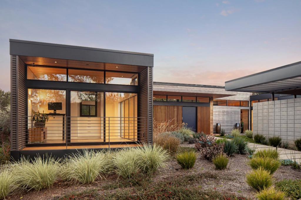 MODULAR, MODERN AND MAGNIFICENT. This home is a striking architectural statement designed with a modular concept and innovative layout. Built with warm wood and industrial-inspired corrugated steel, the exterior presents a bold, linear form that integrates beautifully into the natural surroundings of more than 2 acres. Soaring natural wood ceilings and accent walls complement the expanses of floor-to-ceiling glass, creating a harmonious balance with the outdoors. White oak flooring extends throughout, enhancing the organic aesthetic. Each of the three en suite bedrooms and an office with bath which could be the fourth bedroom is a private sanctuary, housed within its own distinct module yet thoughtfully linked to the central main living areas. Solar-powered, this home is both a design-forward masterpiece and a model of sustainability. Architecture by Swatt-Miers. Builder Forde Mazzola