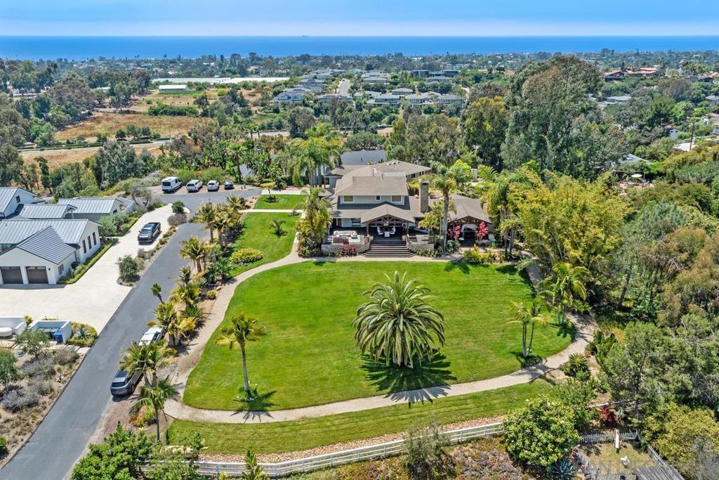 Welcome to Southern California dream living, on over one acre, an incredibly rare large coastal lot with both ocean and golf course views. Hidden at the end of a private road, you'll find incomparable Encinitas privacy, serenity and space. Upon entering the grounds, you are surrounded by lush gardens, mature trees, and beautiful flowers, right in the heart of Encinitas. This spectacular custom estate is an Entertainer’s Dream Home, with 4,464 square feet of living space, and over 1,500 sq ft of Ipe decking & verandas, this home is a true private oasis. The large grassy lawn is the perfect space for a pool, sports court, or ADU. The property is zoned Rural Residential-1 which will allow 2 horses on this parcel, a very rare amenity for the coast. This stunning home offers 3 bedrooms (optional 4th bedroom), 3.5 bathrooms, a bar/billiards/game room, a dedicated office with an ocean view. The open-concept kitchen centers around a large island with seating, Caesarstone countertops. Alder Wood cabinets, 2 sinks, dual Bosch dishwashers, Dacor dual ovens plus warming drawer, 6-burner Dacor stove, and a large walk-in pantry. Enter the large primary suite through double doors to find its own private panoramic ocean-view deck. This property is tucked away on a quiet, private road yet only minutes to SoCals most desirable beaches, and North County's best shopping & dining. Beautiful upgrades throughout include imported exotic Brazilian Mahogany floors, 3 fireplaces with Koa wood & 19th century hand-carved mantels from Indonesia, solid custom doors, custom Tahitian glass fireplace, 3 separate sets of La Cantina bi-fold glass doors, one with a 16' opening to the lanai, outdoor fireplace, and covered deck outdoor dining area. Walk through the superabundant, mature tropical foliage in the private garden, culminating in a secluded tea house from Bali. There is No Homeowners Association to tell you what you can, or cannot do. Do not miss this incredible opportunity to acquire one of Encinitas’ best located, custom homes on over one acre.