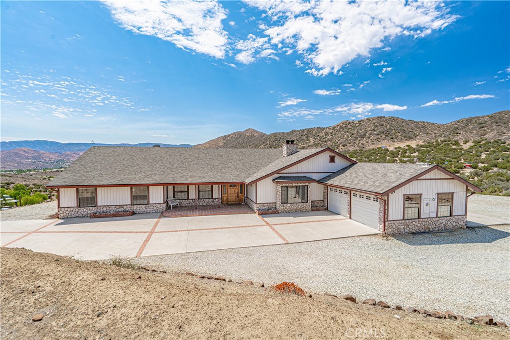 Welcome to your dream escape—an exceptional single-story home offering just under 3,200 square feet of beautifully designed living space, perfectly situated on nearly 10 acres of land with breathtaking panoramic views. Located behind a private electric gate and accessed by a long concrete driveway off paved roads, this hilltop property offers privacy, space, and versatility—all within A2 zoning that allows for a wide variety of potential uses. Step inside to a foyer that leads into a spacious living room with dramatic beamed vaulted ceilings and a warm fireplace. The large formal dining room is ideal for entertaining, while the gourmet kitchen is equipped with stainless steel appliances, including a double oven, a center island with cooktop, and a reverse osmosis system. The kitchen opens directly to the family room, creating a seamless flow that’s perfect for gatherings, with the added comfort of a second fireplace that makes the space feel inviting and connected. Throughout the home, you'll find rich oak cabinetry, solid oak doors, and beautifully crafted oak trim—including casings, baseboards, and molding—that add timeless warmth, charm, and character. This home offers three generously sized bedrooms, an office, and three bathrooms, including a luxurious primary suite with a vaulted beam ceiling, separate his and hers walk-in closets, a jetted soaking tub, walk-in shower, and updated fixtures. The spacious secondary bedrooms provide ample comfort, and the large laundry and mudroom includes a half bath and private entrance—ideal for multi-purpose use or everyday convenience. Comfort is ensured year-round with two newer dual-zone HVAC systems and upgraded ducting, along with individual room wall heaters for added flexibility. Outside, the full-length covered patio—accessible via sliding doors from the family room, dining room, and primary bedroom—overlooks the entire valley with incredible wide-open views. The garage offers two front doors and one rear door for added functionality. This one-of-a-kind home combines rural charm with modern amenities, offering the ultimate in comfort, privacy, and potential. Don’t miss the opportunity to make this incredible retreat your own.