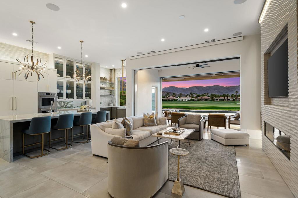 Experience the Pinnacle of Luxury Living at Mountain View Country Club. This extraordinary custom-designed residence that exemplifies refined desert living. Perfectly positioned on an elevated premier lot, the home boasts sweeping, unobstructed vistas of the Santa Rosa Mountains, expansive double fairways, and a tranquil lakefront setting--a view as rare as it is breathtaking. From the moment you step inside, the home welcomes you with a sense of timeless elegance. A dramatic feature wall of architectural stone, custom paneling, and ambient lighting sets the tone for the artistry and attention to detail found throughout. Soaring ceilings, walls of glass, and 24x48 Italian porcelain tile create contemporary grandeur, while curated designer finishes elevate every space. The open-concept great room is anchored by a statement fireplace wall with floating backlit panels and bespoke cabinetry. The formal dining area glows under a brass chandelier, perfect for both intimate dinners and grand gatherings. The custom gourmet kitchen is a chef's dream, featuring a 10-foot Quartzite island, Sub-Zero and Wolf appliances, and a custom wet bar with floating metal-and-glass shelving seamlessly blending function with artistry. The Primary Suite is a serene retreat, offering a Jacuzzi tub, expanded marble-accented shower, and Quartz countertops. Two additional guest suites include en-suite baths with floating vanities, custom closets, and private outdoor access from one suite. A versatile den easily serves as a 4th bedroom, complemented by a stylish 4th bath with marble accents and a custom vanity. Walls of retractable glass open to a resort-style backyard oasis with unobstructed mountain views. Entertain effortlessly around the sparkling pool and spa, built-in BBQ, patio heaters, and drop-down shades--an outdoor sanctuary designed for year-round enjoyment. Mountain View Country Club offers world-class amenities including an Arnold Palmer Signature 18-hole golf course, elegant Clubhouse Dining, a state-of-the-art Fitness Center with Spa services, Tennis and Pickleball courts, Bocce ball, and a Lap Pool. This home is a rare opportunity to own a residence where luxury, comfort, and natural beauty converge seamlessly--a desert retreat that feels like your own private Four Seasons escape.