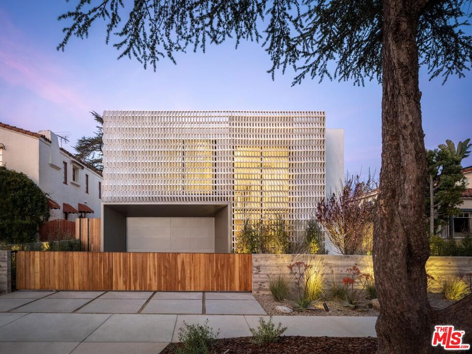 The fully furnished, "Screen House" in Santa Monica, designed by world-renowned architect Hagy Belzberg, stands as a pinnacle of innovative design, earning the AIA LA Design Awards: Single-Family Residential - Honor Award. This award-winning residence seamlessly combines privacy, light, and space with a sophisticated architectural narrative inspired by the family's cultural roots in Mexico City. A handcrafted, porous facade of custom-molded composite blocks ensures privacy while elegantly filtering sunlight, casting dynamic patterns of light and shadow that shift throughout the day. At the heart of the home lies a subterranean courtyard, which infuses natural light deep into the interiors, fostering a sense of openness while maintaining a serene intimacy. Ventilation is masterfully achieved through a triple-height atrium and a northern light well, creating a natural airflow system centered around the courtyard's olive tree. Internally, the home exudes unparalleled craftsmanship, with lighting, millwork, and flooring sourced from Mexico City's top artisans. Renowned millworker Simon Hamui collaborated on custom furnishings, elevating every space with bespoke artistry. The five-bedroom residence includes expansive living and dining areas, a chef-caliber kitchen, a luxurious entertainment suite, elevator and spa-inspired amenities. The basement holds a beautiful screening room, sauna, steam room and gym. With its seamless blend of functionality and aesthetic brilliance, the Screen House is a one-of-a-kind sanctuary, perfect for both retreating and entertaining. Photos by Mike Kelley.