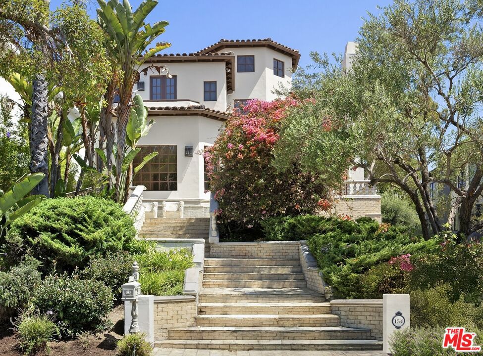 Set on one of Brentwood's most coveted tree-lined streets, this timeless Spanish-inspired estate is surrounded by lush landscaping and designed to balance classic elegance with modern livability. Beyond the striking facade, a beautiful, welcoming entrance introduces interiors filled with natural light, offering both everyday comfort and grand spaces for entertaining. The main level flows seamlessly with a formal living room and fireplace, elegant dining room, spacious family room with bar, sunlit breakfast nook, and a flexible den/office. Upstairs, the primary suite serves as a private sanctuary with a sitting room, fireplace, balcony, dual walk-in closets, spa-like bath beneath a dramatic skylight, and an attached office, while three additional bedrooms provide comfort for family or guests. The lower level offers a media room, bedroom suite, and direct access to an oversized 5-car garage (accommodating up to 6 compact cars). Outside, the backyard is a true retreat with a pool, spa, and outdoor kitchen surrounded by mature landscaping that ensures complete privacy, while multiple patios and terraces create effortless indoor-outdoor living just moments from Brentwood Village, top schools, and the best of the Westside.