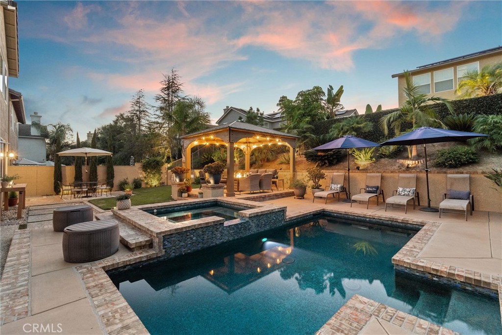 Welcome to Serrano Heights, where the charm of Anaheim Hills meets the convenience of Orange. Tucked on a quiet cul-de-sac, this home blends comfort, style, and an entertainer’s dream backyard.
Step inside to a warm and inviting floor plan, featuring a formal living and dining room, a bright kitchen with high-end appliances, and a family room with a cozy fireplace and stunning backyard views. Downstairs, you’ll find a private guest suite, powder room, and laundry, while upstairs offers a serene primary suite with a sitting area, spa-inspired bath, and a custom walk-in closet. Two additional bedrooms share a Jack and Jill bath, along with a large bonus room perfect for a theater, playroom, or home office.
The backyard is an entertainer’s dream, complete with a sparkling pool and spa, a covered pergola for outdoor dining, lush lawn, and mature landscaping that creates privacy and a true resort-like setting.
Additional highlights include a 3-car tandem garage with great storage, a brand new water heater, and meticulous upkeep throughout the home.
Walk to award-winning Serrano Elementary, enjoy nearby hiking trails and rolling hills, and take advantage of the home’s central location with easy access to both North and South Orange County, freeways, shopping, and dining.
This home is the perfect blend of comfort, lifestyle, and convenience.