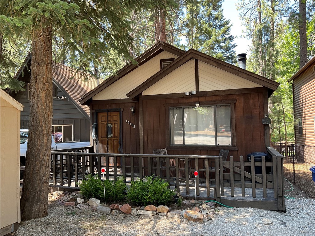 Step into the warmth and comfort of this inviting cabin-style home—ideal for relaxing getaways, hosting family, or enjoying peaceful year-round living. The wood-paneled living room features a blend of cozy seating, soft lighting, and large windows that fill the space with natural light. Thoughtful rustic décor and comfortable furnishings create a welcoming lodge-like feel. The home offers a smart layout with three bedrooms and two bathrooms. The master bedroom is a quiet retreat with its own en-suite bathroom and direct access to the backyard. Step outside to a private patio with outdoor seating and a BBQ—perfect for morning coffee, evening grilling, or soaking up the fresh mountain air. A charming guest bedroom includes two twin beds with matching modern bedding, a shared nightstand, and vintage wall art—ideal for kids or guests. A second full bathroom provides added convenience and comfort for visitors or family members. Inside and out, this home blends cozy cabin charm with everyday functionality. The fenced backyard, thoughtful furnishings, and balance of shared and private spaces make it well-suited as a personal residence, vacation home, or future rental opportunity.