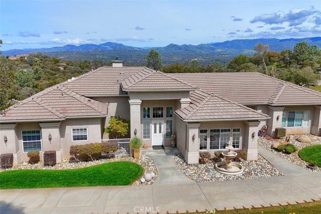Set on a lovely 4.51+/- acre property that offers gorgeous mountain views, you will go through the gated entrance and travel the concrete driveway lined with charming street lamps to be greeted by a custom dream home! From the beautiful entry to the breathtaking views from the living room, you will appreciate the open feel throughout. The great room has 10 ft. ceilings, a cozy fireplace and flows to the dining room that includes a built-in hutch, wine rack, a wet bar with quartz countertops and a sliding door leads to the covered breezeway. A separate office with French doors is just steps away where “working from home” is convenient. A fabulous kitchen with 10 ft. ceiling has a long center island with quartz countertop, deep composite sink, dishwasher and breakfast bar. A built-in stovetop, built-in oven and microwave, and a walk-in pantry with gleaming cabinets and recessed lighting. A sunny breakfast area offers views and a great spot for informal dining. A grand primary suite will be your private oasis! The peaceful mountain views will add to the serenity with a sliding glass door to the patio and a double-sided gas fireplace. The ensuite primary bathroom includes a double-headed shower, a separate soaking tub to enjoy the double-sided fireplace, double vanities, walk-in closet and a private water closet. 2 guest bedrooms have walk-in closets and have a Jack ‘n Jill bathroom also with double vanities and a tiled tub/shower. A large utility room has plenty of room for your laundry with a sink and plenty of storage. The covered patio will be one of your favorite places but take the steps down to a lower patio atop a granite outcrop, landscaped yard, RV parking, and a potential site for building a workshop. Located near Yosemite and Bass Lake, this truly is a custom beauty you won’t want to miss!