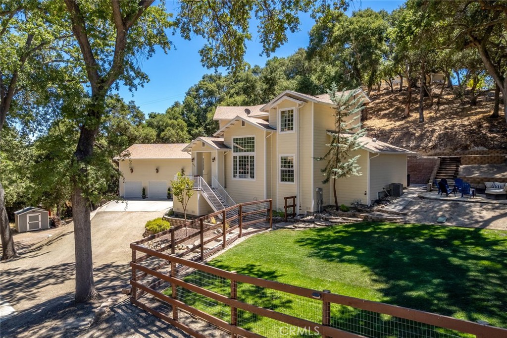 Experience the best of the Atascadero lifestyle in this thoughtfully designed home, perfectly situated on a serene one-acre parcel nestled among majestic oak trees.
The main residence features hard-surface flooring throughout and expansive dual-pane windows that flood the interiors with natural light. A double-sided fireplace connects the living room and family room/office, while the open-concept layout on the main level includes a built-in desk area and custom cabinetry. The gourmet kitchen is beautifully appointed with granite countertops, stainless steel appliances, and a center island, seamlessly connecting to the dining room, where French doors open to a tranquil rear patio—an ideal space for gatherings and outdoor entertaining.
The luxurious primary suite, located on the main level, offers a cozy fireplace, spa-like bath with a jetted tub, dual-sink vanity, and a spacious walk-in closet. This main level also features a dedicated laundry room with a sink, folding area, and its own outdoor access.
Upstairs, an oversized bedroom with its own fireplace and walk-in closet provides the flexibility of a second primary suite. Two additional bedrooms and a bathroom complete the second level. Additional highlights to the estate include a great outdoor area under the oak trees with a bonfire pit, along with a large grass area with a sprinkler system. Detached from the main home is a finished 3-car garage, with finished floors and a half bath - perfect for a game room, or creative use. Above the garage is a separate guest quarters featuring a full kitchen, two bedrooms, and a bathroom. The suite features its own entrance and hard-surface flooring—perfect for visitors, extended family. The driveway offers space for an RV, boat, or recreational vehicle parking. Blending privacy, functionality, and thoughtful design, this property is a rare offering that brings together everyday comfort and exceptional versatility—an ideal retreat to call home in the heart of Atascadero.