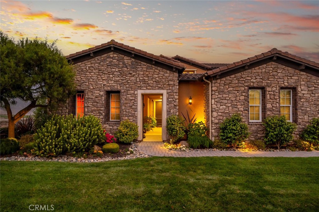 This stunning, stone-clad architectural masterpiece offers a rare blend of timeless elegance and natural serenity. Surrounded on three sides by open golf course fairways and graced by a tranquil lake, the setting maximizes openness, privacy, and peaceful views. Step through a charming private courtyard into a refined 3,724 sq ft residence where thoughtful design meets effortless livability. The interior showcases a harmonious blend of indoor and outdoor living, with expansive floor-to-ceiling windows and direct access to a generous patio and manicured gardens—perfect for entertaining under the California sun. Designed to live like a single-story home yet spacious enough for every occasion. The spacious main-floor has all your main living areas including a deluxe primary suite with a sitting area, a guest suite, formal and casual living spaces, a gourmet kitchen, and a separate office—creating the comfort and convenience of single-level living. Upstairs, a bonus room and additional guest bedroom offer ideal space for family visits, hobbies, or a private retreat. From the moment you enter, rich hardwood floors and picturesque views set the stage for a home filled with natural light and refined comfort. The chef’s kitchen is equipped with stainless steel appliances, white cabinets with pull-out drawers, a built-in refrigerator, and a dry bar—perfect for hosting gatherings. Outside, the beautifully landscaped 9,609 sq ft lot includes a covered patio ideal for relaxing or entertaining while soaking in the spectacular lake and golf course views. The oversized lot also features a generous side yard, perfect for gardening or additional outdoor enjoyment. Special features include hardwood floors, solar energy, a private entry courtyard, fireplace, office with built-in cabinetry, upgraded kitchen and baths, and a sumptuous primary suite with an extra-large walk-in closet and sitting area. A three-car garage and washer and dryer are also included. This is more than a home—it’s a lifestyle, offering stunning long-range views, a desirable and flexible floor plan, and impeccable finishes throughout.