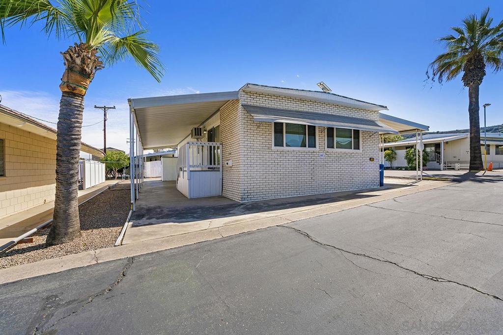 Low space rent. 55+ community. Corner lot with dual entry carport where at least three cars can fit. Situated next to the community laundry room. Home also has laundry hooks inside. Large lot with a lot of room surrounding the unit. Spacious main bedroom with remodeled bathroom and dual closets. Second bedroom has good space. Hall bath in serviceable condition. Window AC unit, newer sliding glass door and dual pane windows throughout. Newer decking/stairs, dining area with a built-in hutch. Newer water heater. This home is older but has been maintained. Carpets cleaned recently. Narrow hallway as the unit was built in 1965. This is a rent control park which means the space rents do not go up with each sale and must be approved per government guidelines on a yearly basis. Nice storage unit in the rear and plenty of space. Corner lot with community laundry room to one side which makes it for a minimum number of neighbors abutting the home site. The park has RV storage and boat parking slots available for an extra monthly fee. Unit has storage shed in the rear. Owner pays tag fees yearly not property taxes.
