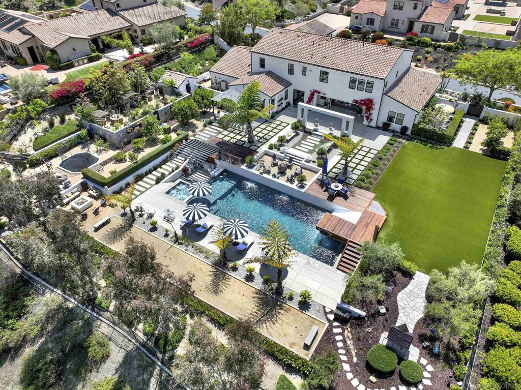 Priced from $4,995,000 to $5,175,000 — A rare opportunity to own a resort-style estate in The Lakes, set on just under an acre and backing to open space with a scenic lake and cascading river. This luxury home offers the ultimate Southern California lifestyle with a private, attached guest suite—ideal for multigenerational living. The suite includes its own entrance, living room, kitchenette, bedroom, full bath, laundry, and secluded yard. The resort-inspired backyard features a spectacular pool with waterfalls, dual slides, diving decks, spa, custom Baja shelf, and a one-of-a-kind zipline. Entertain effortlessly with a sunken BBQ area (featuring a viewing window into the pool), al fresco dining under the modern pergola, and seven fire features, including three cozy fire pits. Additional highlights include a whimsical playhouse, secret stone-walled organic garden, sunken trampoline, bocce court, expansive turf lawn, and pool bathroom with shower and sauna. Inside, the home impresses with elegant architectural design, a flowing open-concept layout, natural light, and panoramic views. Optional purchase includes the designer furnishings and/or a Crosby Club golf membership valued at $30,000. This is more than a home—it’s a lifestyle destination.