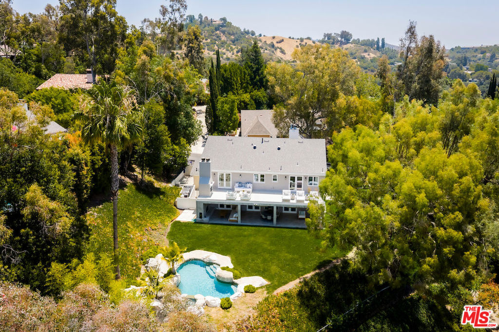 Discover the magic of coming home to this one-of-a-kind, gated retreat with serene views - the only house on the block where every sunrise and sunset feels like a private celebration. Perfectly set in a 24-hour security-patrolled area with four community tennis courts, sidewalks for walking, and double-wide streets offering endless parking to live and entertain with ease. Surrounded by nature yet minutes from the heart of Beverly Hills and the Valley, this four-bedroom, four-and-a-half-bath estate offers a rare blend of space, privacy, and luxury. This unique home is wrapped with an oversized grassy yard, all looking out to the spectacular views. Bathed in natural light throughout the day, all main living spaces are thoughtfully oriented to face west, south, and east, capturing the warmth of morning light and the golden glow of breathtaking sunsets. Elegant marble and hardwood flooring throughout the first floor adds a touch of warmth and sophistication, perfectly setting the tone for both grand entertaining and quiet family moments. The kitchen, open to the family room, is a chef's delight with its Sub-Zero refrigerator, Viking stove, Bosch dishwasher, and built-in breakfast table. Just steps away, the family room opens seamlessly to the oversized covered outdoor patio with built-in heaters through French doors, blending indoor and outdoor living. Upstairs, the primary suite is a true retreat, featuring hardwood floors, vaulted ceilings, a sitting room with a fireplace, and French doors leading to a brand-new balcony. This balcony, designed with sleek glass railings to preserve the stunning views, even has its own outdoor fireplace an ideal spot for morning coffee or sunset reflections. The primary bathroom is a serene sanctuary, offering privacy, natural light, and views that soothe the soul. Each bedroom is designed with its own ensuite bathroom, ensuring comfort and privacy for everyone. There's also a private office upstairs. Ample storage includes a three-car garage and three additional gated parking spots, plus the peace of mind that comes with a brand-new 2025 roof with a 50-year warranty. Zoned for the highly sought-after Warner Avenue Elementary School District and central to several top private schools, this home is an ideal choice for families seeking both space and top-tier education. This remarkable property truly stands apart a place where memories are made, sunsets are celebrated, and the good life comes naturally.