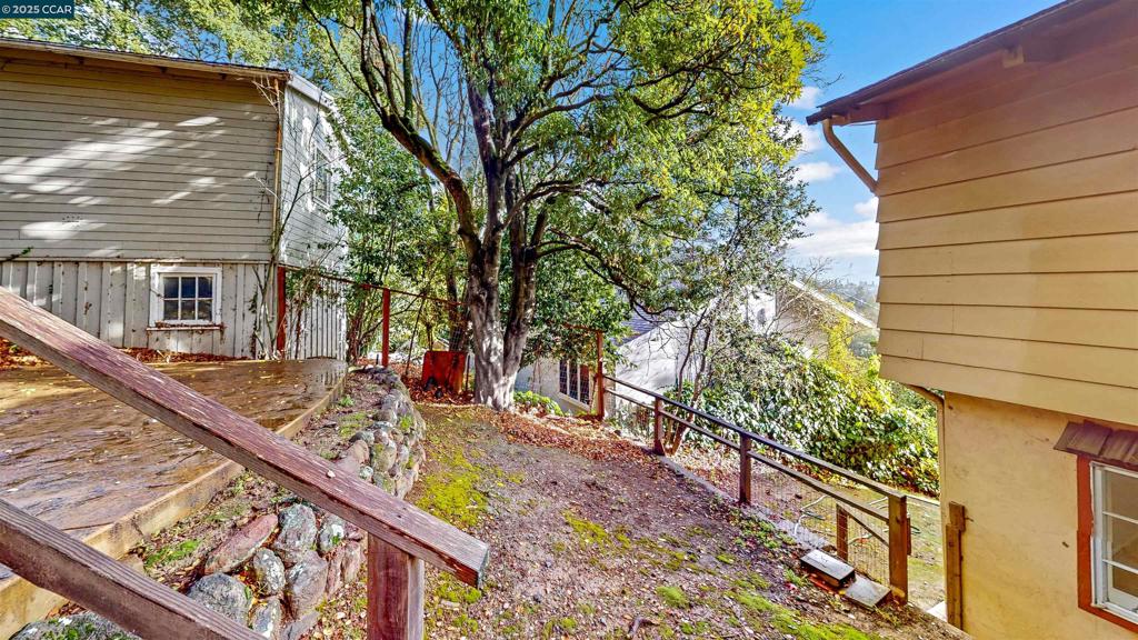 Step into timeless California charm with this beautifully updated 1925 cabin-like home, offering the perfect blend of rustic character and modern comfort. The main residence spans 1,538 square feet and showcases a welcoming stone fireplace, hardwood floors, wood windows, exposed beam ceilings, and classic paneling that reflect the home’s original craftsmanship. A remodeled kitchen with natural wood cabinetry and upgraded stainless steel appliances—including a gas cooktop, double ovens, built-in microwave, and dishwasher. The layout features three spacious bedrooms, one conveniently located on the main level and two upstairs with a full bathroom. The lower-level studio, offering 438 square feet, includes a private entrance, tile floors, fresh paint, a full kitchen, separate bathroom and a versatile space for guests, extended family, or rental income. Surrounded by stately oaks, the property captures the essence of nature with stamped concrete walkways, patios, and filtered views of downtown Oakland. A spacious two-car garage/storage unit sits at the top of the lot. Just minutes from downtown Montclair, this home offers the convenience of nearby shops, restaurants, and grocery stores, along with easy access to Highway 13 and a quick connection to Highway 24 for commuting.