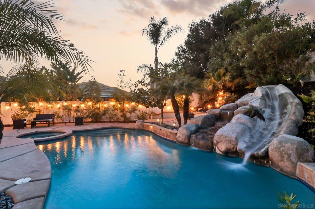 Tucked away on an expansive corner lot in a tranquil cul-de-sac, this exquisite resort-style residence is located within the prestigious gated community of Rancho San Pasqual. Enveloped by lush mature landscaping and framed by serene hillside vistas, the home offers an unparalleled blend of sophistication, privacy, and relaxed elegance. Enter to discover a designer-curated interior, where a recently remodeled gourmet kitchen becomes the centerpiece—featuring gleaming quartz countertops, a 5-burner cooktop, dual convection ovens, wine refrigerator, and custom tile backsplash. Perfect for refined entertaining and everyday indulgence, the space flows effortlessly into a spacious great room, formal dining area, and a separate living room—all adorned with luxury vinyl plank flooring, plantation shutters, and dual-zone climate control. The lavish primary suite is a serene sanctuary, complete with a spa-inspired en-suite bathroom and a generous walk-in closet. A versatile downstairs bonus room serves beautifully as a guest suite, executive office, or playroom. Outside, your private backyard retreat awaits: a shimmering resort-style pool with waterslide, a fully equipped outdoor kitchen with built-in BBQ, and a tranquil hidden garden ideal for reflection or cultivating fresh herbs. The property also boasts a lush mini orchard bearing mango, peach, persimmon, tangerine, and apple trees. Enhanced by premium upgrades including retractable screen doors, a Tesla EV charger, and solar panels, this turnkey estate embodies the essence of luxurious Southern California living. Only a short 13 min drive to the nearest shopping and dining areas!!!!