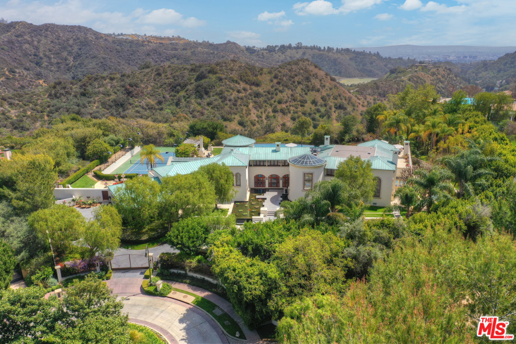 Spectacular, ultra-private estate in exclusive guard gated North Beverly Park. Coveted rim location at the end of private cul-de-sac affords sweeping city/canyon/mountain views & seclusion. Inside its gates, property is an oasis of solitude & beauty, offering captivating gardens & stunning interiors. Floor to ceiling glass & soaring ceilings enhance volume & light & provide beautiful vistas of the enchanting grounds. Property is perfect for sophisticated large-scale entertaining or quiet, private relaxation. This is a true serene retreat that is only minutes from the city, allowing easy access to Beverly Hills, DTLA, or the Valley studios. Refined interiors include an indoor pool, gym, theatre, game room, elegant large public rooms, a marvelous library/office, his & her master baths, 5 ensuite bedrooms, & more. Expansive terraces wrap around the second level flowing out from each bedroom. Huge terrace off master provides private staircase to spa & gardens. The amazing grounds include