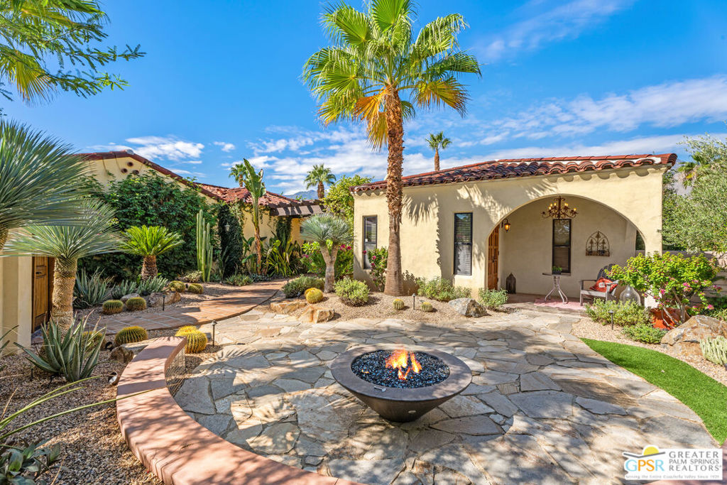 Nestled in the heart of Araby, one of Palm Springs' most coveted neighborhoods, this stunning residence combines the look of traditional Mediterranean and Spanish architecture with all the modern amenities. Sitting on land that you own, and with no HOA fees, this four-bedroom, four-bathroom home offers an exceptional blend of comfort and sophistication. Located on a private street with its own security gate, you drive up to this exceptional home that boasts a direct access 3-car garage with additional driveway parking. As you enter the property through the front gates, you are surrounded by a lushly landscaped courtyard, complete with its own firepit and conversation seating area. The Saltillo tile pathway leads to the rustic alder double entry doors. Through the doors, the view of Mt. San Jacinto takes your breath away. The charm continues with a layout that emphasizes open spaces and abundant natural light. The wood-clad vaulted ceiling with exposed wooden beams and numerous archways add to the property's architectural allure, while the slate flooring provides a rustic touch. Sit down to enjoy an intimate evening with friends in front of the fireplace or use the entire expanse of the great room to entertain a crowd. The gourmet kitchen features a large central island, expansive breakfast bar and modern appliances, but the slate floors seamlessly integrate the rustic charm throughout. A separate family room adjacent to the kitchen offers another space for TV viewing or intimate gatherings. The primary bedroom features a cozy fireplace and stunning mountain views through 2 sets of double doors. The large ensuite bathroom boasts a long double vanity with beautiful copper sinks. You will also find a separate tub and shower and abundant natural light, providing a truly indulgent retreat. There are three additional bedrooms; two with ensuite bathrooms and one with a private entrance and patio. The free form pool and spa on the over-sized lot is complemented by the gazebo and outdoor barbeque area. There is a large, covered patio for al fresco dining and it provides the perfect setting for entertaining or just watching the sunset over the mountaintops. Don't miss your opportunity make this exceptional residence, located on historic Anza Trail, your own!