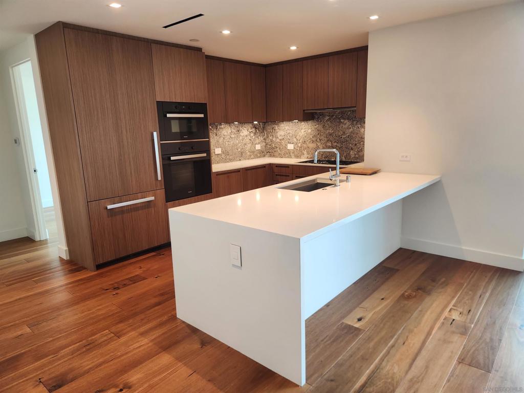 Live life well in this modern, spacious condo in The Park at Bankers Hill, a luxurious 7 year new building fitted with beautiful stone and wood throughout. Inside the home is a well appointed gourmet kitchen with high end Miele appliances, including a wine frig. Off the kitchen is a large full size laundry room. The primary bedroom features Balboa Park views, a super luxe large en suite bath plus a BIG walk in closet. The second bedroom is located away from the primary suite on the far side of the large great room and provides everyone with maximum privacy. Floor to ceiling windows and nine foot ceilings in every room bring lots of joyful light in. A large, well proportioned balcony off the great room has pleasant views of Balboa Park and a gas line for your grill, so there's no hassling with refilling propane tanks. The amenities in this luxurious condominium building (much better than a lease apartment building) are outstanding! They include a large well equipped gym, a large pool that's well suited for lap swimmers, a steaming hot tub, and a very nice outdoor picnic area with tables, lounges and grills. There is also a large party room facilitated by two separate kitchens and a separate club room with a billiard table and wine storage. The gated and fully enclosed parking garage with two private side by side parking spaces make coming and going easy. Inside, three fully secured elevators serve just 60 homes; there is very little waiting for an elevator. The impressive lobby with 24 hour doorpersons keep you safe. Lot of glamorous luxury- you deserve it!