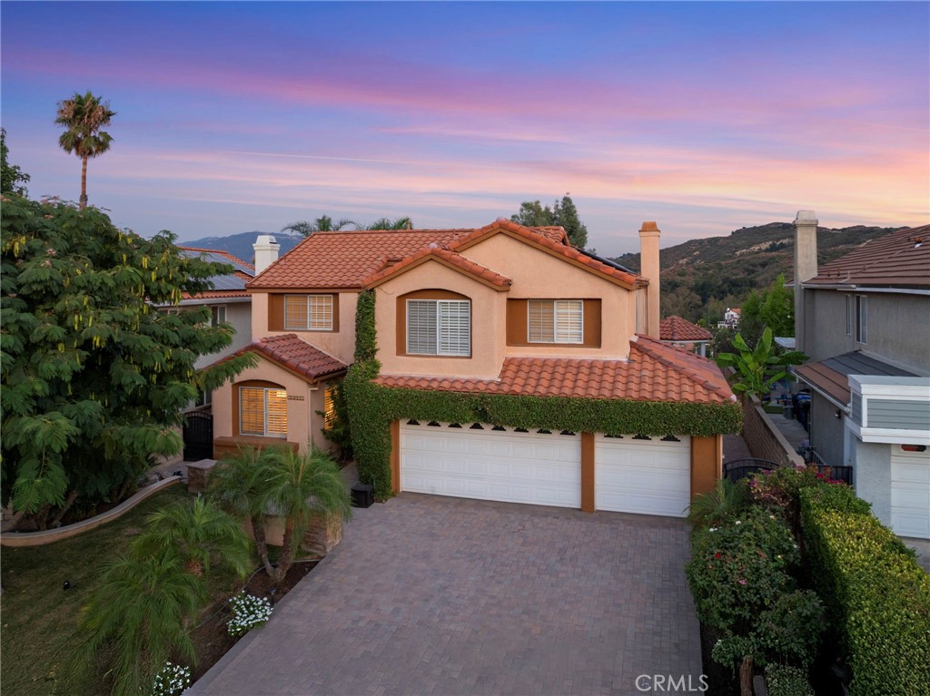 Welcome to 24512 Skyridge Drive, a beautifully upgraded 5-bedroom, 3-bathroom home tucked away on a quiet cul-de-sac in Newhall’s highly sought-after Hidden Valley community. With 3,059 sq. ft. of living space on a 7,050 sq. ft. lot, this residence blends style, comfort, and entertainer’s appeal. Inside, the living room features soaring beamed ceilings and a fireplace, while the expansive family room showcases a wet bar and French doors leading to the backyard. The kitchen is designed with granite countertops, recessed lighting, stainless steel appliances, a breakfast nook, and tile flooring. A downstairs bedroom with double French door entry and walk-in closet provides the perfect setup for guests or multi-gen living. Upstairs offers a loft, three spacious guest bedrooms, and a primary suite with a beautifully updated bathroom and French doors opening to a private balcony with expansive mountain views. Upgrades include engineered hardwood flooring throughout, plantation shutters, freshly painted interior and exterior, dual-zone HVAC (2025), solar lease at just $160/month, and a fully redone roof (2020). The 3-car garage is a dream with perimeter storage cabinets and pull-down attic storage. Step outside to a true entertainer’s paradise: a granite-tiled outdoor kitchen with built-in BBQ, dual gas burners, sink, mini fridge, and outdoor TV. A covered gazebo, paver-lined patio, small grassy play area, and sweeping 180° mountain views complete this incredible retreat. Enjoy resort-style Hidden Valley HOA amenities: pool, spa, tennis and pickleball courts, private park, playground, hiking trails, and gated RV/boat storage. Convenient access to the 5 freeway makes commuting easy while keeping you close to the best of Santa Clarita Valley living.