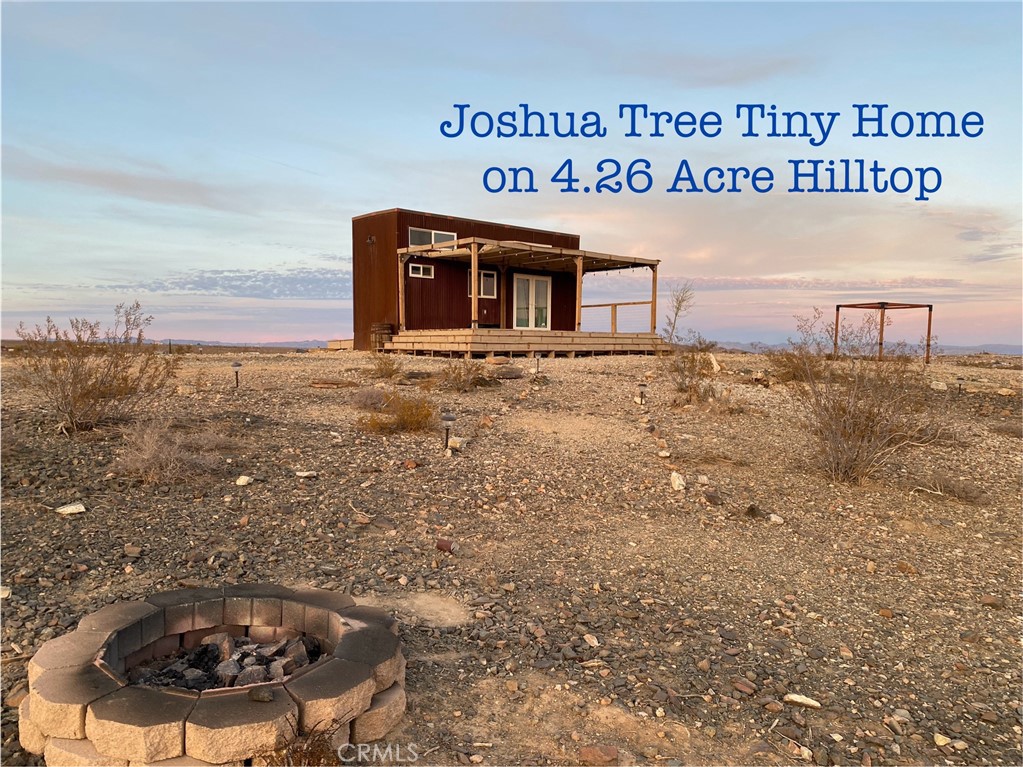 Joshua Tree hilltop tiny home on 4.26 acres. Come discover the view from this Mojave Desert extraordinary location. Live off the grid independently with this solar powered house. Enjoy the sunrises and sunsets from the large cover patio deck. You will have privacy with expansive views in all directions. Located just a short drive from the Village of Joshua Tree, the Joshua Tree National Park, and all the nearby Bureau of Land Management public lands for recreation. The property features a mini-split heating and cooling system, a tankless hot water heater, 3k watt solar power system with batteries, 3k on site water storage, and 300-gallon wastewater holding tank. Ample parking for vehicles including RV's. Make an appointment to tour this unique desert opportunity to own your own acreage with priceless views.