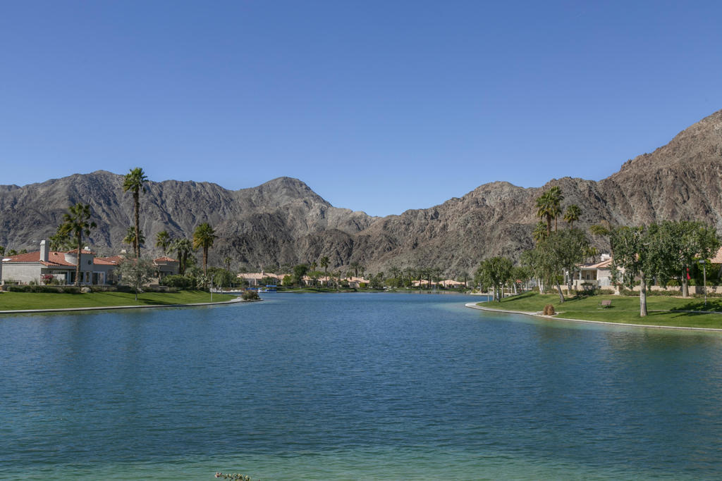 Welcome to Laguna De La Paz, a prestigious guard-gated lake community in the heart of La Quinta, offering the best of desert living. This beautifully updated 3-bedroom, 3-bath home boasts 1,980 sq. ft. of living space on a large, private pie-shaped lot. Step into a spacious great room with a cozy fireplace, adjacent to a flexible dining area or den, and an open-concept kitchen featuring modern updates and a charming breakfast nook.The primary suite is generously sized, offering space for a sitting area, a large walk-in closet, and an ensuite bath with dual vanities, a soaking tub, and a walk-in shower. On the opposite wing, you'll find a private guest ensuite and a third bedroom with an additional full bath--ideal for visitors or a home office. Both the primary bedroom and kitchen feature sliding glass doors that open to a covered patio, perfect for entertaining or enjoying serene mountain views. The backyard includes a grassy area--great for pets or outdoor fun.Community amenities are exceptional: 15 pools, 16 spas, a scenic lake with paddle and electric boats, tennis and pickleball courts, a fitness center, and more. All located near world-class golf, dining, shopping, entertainment, Old Town La Quinta, and the iconic La Quinta Resort & Spa.