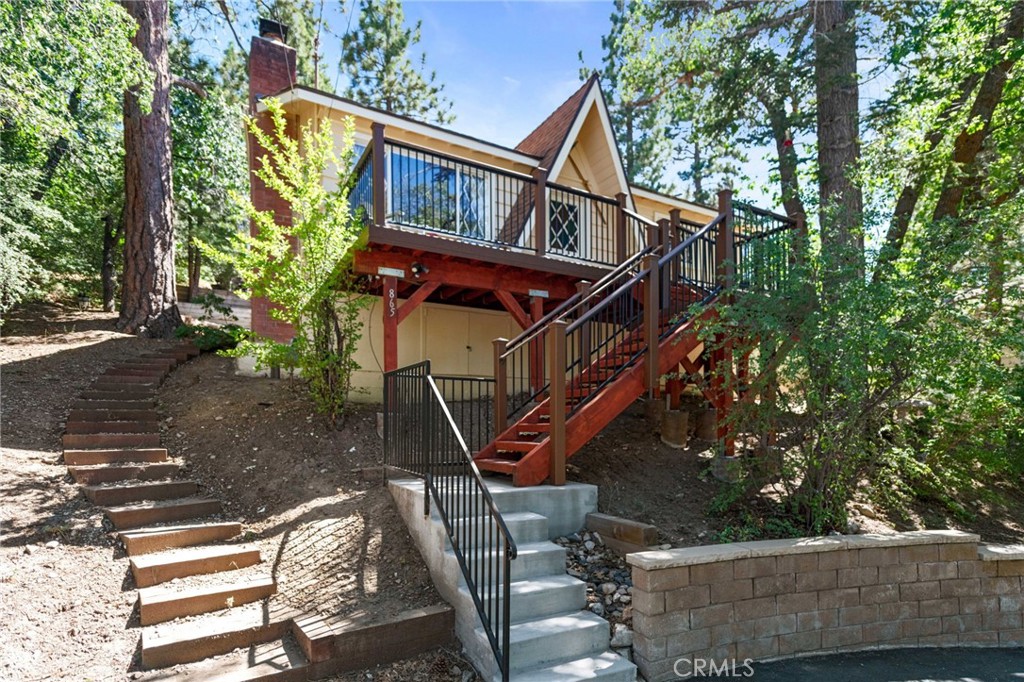 Perched among oaks and pines, this charming chalet has treehouse vibes that make stress fade away. An easy connection to nature is complemented by a prime location, with Moonridge’s best attractions under 5 minutes away—from the ski slopes & golf greens of Bear Mountain, to local gems like the Alpine Zoo, Moonridge Coffee, and Dank Donuts. The interior has been meticulously reimagined, with every detail considered to create something truly one-of-a-kind. Low ceilings have been replaced with open timber beams, and nature-inspired elements like wide-plank pine floors and an adobe-style fireplace add to the home's unique charm. Bar seating effortlessly connects to a thoughtfully designed kitchen, featuring granite counters, a Thermador convection oven, and a wall-mounted faucet, highlighting the care and craftsmanship that define this extraordinary home. Natural light flows in through a large picture window, and sliding glass doors open to a yard that feels hidden away, with tiered planter beds & automatic sprinklers. Two bedrooms are cozy places to unwind, with one bedroom intentionally left open to the living room to provide a flexible and flowing space. Curtains here offer a buffer, but inset beams create the option to add walls for privacy. In the bathroom, travertine tiles are upscale, with a dreamy sunken jetted tub & shower looking out on blue skies and leafy oak trees. Additional upgrades include a U-shaped driveway with ample parking, low-maintenance composite decking, and a convenient storage loft. Begin your next adventure in this incredible turn-key retreat, where thoughtful upgrades and a prime location offer the best of Big Bear.