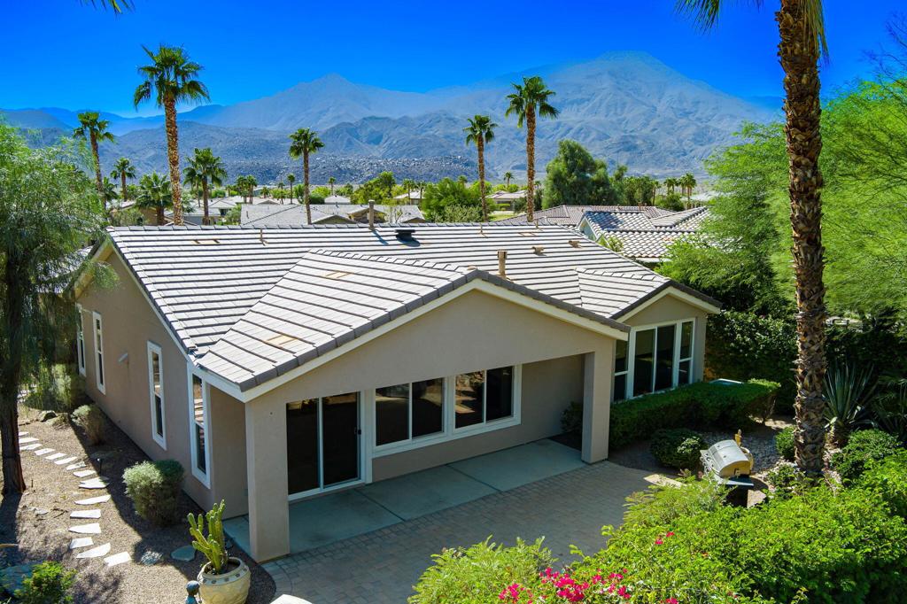 Nestled on a quiet cul-de-sac within the gates of the premier 55+ community of Trilogy La Quinta, this classic Monterey plan with detached casita offers 1,965 sq. ft. of thoughtfully designed living space, including 3 bedrooms, 3 baths, and a versatile den/office that may serve as a 4th bedroom. A wrought iron privacy gate and Tuscan-style facade open to a welcoming courtyard with custom pergola, setting the tone for the home's inviting ambiance. The great room features built-in shelving, a tile-encased fireplace with mantel, and expansive rear yard views, seamlessly connected to the dining area and well-appointed kitchen complete with a generous prep island and bar seating, slab countertops, custom backsplash, dual ovens, microwave, gas cooktop, black appliances, abundant cabinetry with brushed nickel hardware, and a spacious pantry. Multiple guest accommodations include a private detached casita with beverage center and sink, ideal for hosting family and friends in comfort. The primary retreat showcases a bay window, French door access to the backyard, and an en suite bath with dual sinks, vanity, slab countertops, a large tiled shower, and a walk-in closet. Outdoors, tranquility abounds with a paver patio, professional landscaping, and a covered patio, creating an ideal setting for relaxation and entertaining.