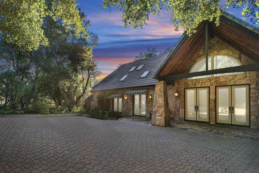 Discover timeless elegance and privacy in this custom-designed Country French Estate on 4.52 acres bordering the prestigious De Luz community. This exquisite 4,303 sq. ft. home features 4 bedrooms, 5 baths, and two private office rooms, offering an exceptional blend of sophistication and comfort. The stunning brick and stone exterior is surrounded by 200+ mature oak trees, creating a peaceful, park-like setting. The gourmet kitchen showcases custom cabinetry, stainless steel appliances, and a 12-foot granite island—a dream for cooking and entertaining. The great room includes a fireplace, wet bar, built-in entertainment center, and full sound system. Elegant hand-scraped oak floors and French doors bring warmth and charm throughout. The main-floor primary suite offers a fireplace, Carrara marble bath, steam shower, soaking tub, and dual walk-in dressing rooms. A second bedroom or office is conveniently located on the first floor. Upstairs features a private guest retreat with two ensuite bedrooms, full baths, kitchenette, and living area. The gated property includes a stamped-concrete driveway, parking for seven vehicles plus an RV, and an outdoor Argentine kitchen with grill, wood-fired pizza oven, sink, and granite counters. Room to add a pool, horse barn, or studio. Ideally located near Temecula Old Town, wineries, shopping, and within the Murrieta School District—this home embodies luxury, privacy, and California living at its finest.  Welcome to this one-of-a-kind Country French Estate, a masterpiece of custom design, quality craftsmanship, and timeless beauty. Perfectly situated on 4.52 private acres bordering the exclusive De Luz community, this 4,303 sq. ft. residence blends European charm with modern comfort, creating a home that feels both grand and inviting.  From the moment you enter the gated driveway, you’ll be surrounded by the serenity of nature — over 200 mature oak trees, gentle breezes, and the sound of birdsong. The brick and stone exterior evokes classic French architecture, while the property’s natural landscape provides complete privacy and peaceful seclusion.  Inside, the attention to detail is evident at every turn. The gourmet kitchen is a chef’s dream — featuring custom-built cabinetry, professional-grade stainless steel appliances, and a magnificent 12-foot granite island that serves as the centerpiece for cooking, gathering, and entertaining. Whether hosting intimate dinners or large celebrations, this kitchen is designed for both functionality and elegance.  The expansive great room includes a beautiful fireplace, a full wet bar, built-in entertainment center, and surround sound system — creating an inviting space for relaxation or entertaining guests. Throughout the home, hand-scraped oak flooring, French doors, and high ceilings enhance the open, airy feel while maintaining warmth and character.  The main-floor primary suite offers a true retreat — complete with a cozy fireplace, French doors opening to the backyard, and a spa-inspired ensuite bathroom. Enjoy Carrara marble countertops, a glass-enclosed steam shower, a luxurious soaking tub, and dual walk-in dressing rooms with custom cabinetry. A second bedroom or office is also located on the main level, ideal for guests or working from home.  Upstairs, the design caters beautifully to extended family or guests with a private retreat that includes two ensuite bedrooms, two full bathrooms, a living area, and a complete kitchenette — perfect for multi-generational living or hosting friends with comfort and independence.  Two dedicated office rooms make this home ideal for professionals or creatives who value both productivity and peace. Whether used as private workspaces, a library, or hobby rooms, these flexible spaces add exceptional versatility.  Outdoors, the estate is equally impressive. A large covered patio overlooks the backyard, providing the perfect setting for morning coffee or evening gatherings. The custom-built Argentine outdoor...