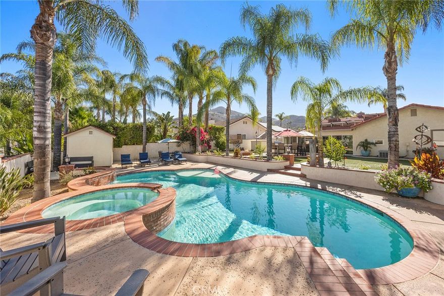 Welcome to your own private resort, where vacation living meets everyday comfort. This beautifully updated single-story home is perfectly positioned on a large, level cul-de-sac lot within the highly desirable guard-gated community of Canyon Lake. Surrounded by over twenty mature Queen palms, custom stamped concrete, and lush low-maintenance turf, this property exudes an effortless tropical elegance that immediately transports you into relaxation mode.  Step inside and you’ll find a well composed floor plan with no interior stairs, cool tile flooring throughout, and newer dual-pane Pella windows and solar tubes that fill the space with natural light. The kitchen is both stylish and functional, featuring Brazilian granite countertops, a farmhouse sink, soft close cabinetry and premium appliances including a KitchenAid range and refrigerator, Bosch dishwasher, and built-in microwave. Every detail reflects thoughtful upgrades and modern comfort, from the whole-house fan and efficient pellet stove to central air and heat.  Designed for entertaining, the backyard feels like a private oasis. A sparkling pool and spa—equipped with new heater and new pump—invite you to unwind under the palms, while the built-in outdoor kitchen with BBQ island, warming tray, and bar seating makes hosting effortless. Evenings can be spent gathered around the cozy in ground fire pit, while enjoying the easy indoor-outdoor flow that defines California living.  Energy-efficient features include PAID OFF SOLAR PANELS and NEW whole house reverse osmosis water system, ensuring sustainable comfort year-round. The attached two-car garage offers epoxy floors, built-in cabinets, a workshop area, plus tons of storage space both inside and out.  Located just minutes from Canyon Lake’s private golf course, boating, lodge and lakeside amenities—close to local wineries and casinos—this move-in ready home offers the perfect blend of luxury, leisure, and lifestyle. Every element has been designed to make daily life feel like an endless vacation, so make your best offer today before it is gone.