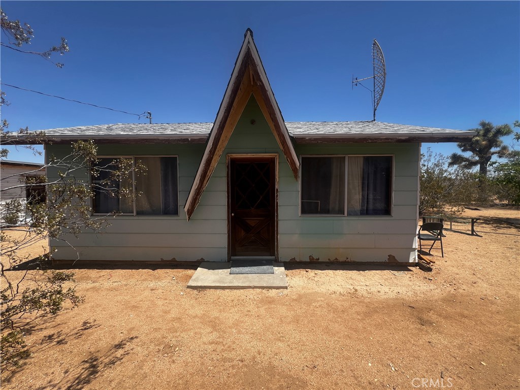 Welcome to 1489 Balsa Avenue, a charming single-family studio-style home situated on a spacious 5-acre desert lot in Yucca Valley. This unique property offers rustic appeal with a distinctive A-frame entry, mature Joshua Trees, and wide-open views of the surrounding landscape. The home has received some thoughtful updates over the years, including exterior paint, roofing, and functional improvements that support comfortable desert living. Inside, the open layout offers flexibility for sleeping, lounging, and working, while the vintage wood paneling adds a warm, retro touch. Outside, the property includes a secondary structure with power already in place—an ideal opportunity for a future guesthouse, art studio, or workshop with additional development potential. The lot is only partially fenced, providing ample room to expand, customize, or create your own desert sanctuary. Whether you’re looking for a full-time home, creative retreat, or long-term investment, this one-of-a-kind desert dwelling has potential written all over it.