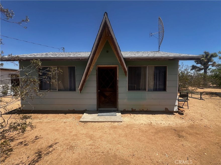 Welcome to 1489 Balsa Avenue, a charming single-family studio-style home situated on a spacious 5-acre desert lot in Yucca Valley. This unique property offers rustic appeal with a distinctive A-frame entry, mature Joshua Trees, and wide-open views of the surrounding landscape. The home has received some thoughtful updates over the years, including exterior paint, roofing, and functional improvements that support comfortable desert living. Inside, the open layout offers flexibility for sleeping, lounging, and working, while the vintage wood paneling adds a warm, retro touch. Outside, the property includes a secondary structure with power already in place—an ideal opportunity for a future guesthouse, art studio, or workshop with additional development potential. The lot is only partially fenced, providing ample room to expand, customize, or create your own desert sanctuary. Whether you’re looking for a full-time home, creative retreat, or long-term investment, this one-of-a-kind desert dwelling has potential written all over it.
