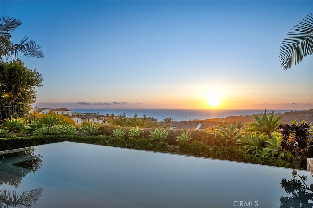 Welcome to this breathtaking luxury estate located in the exclusive, guard-gated enclave of Crystal Cove in Newport Coast. Perched high above the Pacific, this extraordinary residence offers panoramic ocean, canyon, and coastline views that create a truly serene and private retreat. This custom-designed masterpiece blends timeless Mediterranean elegance with contemporary sophistication. From the moment you arrive, you're greeted by exquisite curb appeal: rustic stone accents, terracotta rooflines, and a peaceful, tree-lined driveway that sets the tone for the home's serene and elevated ambiance. A gracious arched entryway leads into a luminous foyer and tranquil interior courtyard, framed by architectural columns and punctuated by a sculptural water feature — a design centerpiece that blurs the line between indoor and outdoor living. The heart of the home is a light-filled great room, seamlessly flowing into the gourmet kitchen and dining spaces. A dramatic arched window showcases panoramic coastline views, while the open-concept floor plan is anchored by high ceilings, honed limestone flooring, and custom wood detailing throughout. The chef’s kitchen is outfitted with premium Sub-Zero appliances, an oversized island with waterfall-edge countertop, and an artful tile backsplash. The adjacent formal dining room offers two sets of French doors to the courtyard and a stunning custom geometric feature wall — ideal for entertaining in any season. This home features 4 bedrooms and 3.5 bathrooms, including two main-level bedrooms — one of which serves as a second primary suite or private guest quarters. Upstairs, the primary suite is a true sanctuary with a private ocean-view Juliet balcony, spa-inspired bath with tub, and views that stretch across the coastline. An additional en-suite bedroom and a fully built-out home office/loft with rich wood cabinetry complete the upper level. Step outside your own resort-style backyard where a luxurious infinity-edge pool/spa, lush landscaping, and a custom-built fire feature overlook the sparkling Pacific. Multiple lounge areas, an outdoor kitchen with built-in BBQ, and a shaded dining pavilion invite unforgettable sunset gatherings and elegant al fresco living. Located in the 24-hour guard-gated community of Crystal Cove, residents enjoy access to private Canyon Club amenities, dining and shopping at Crystal Cove Promenade, miles of pristine beaches, scenic trails, and top-tier Newport Coast schools.