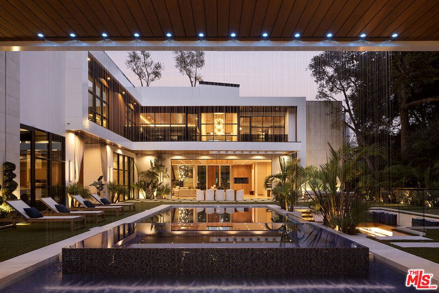 Indulge in an effortless resort-quality lifestyle from this extremely private entertainer's compound surrounded by natural greenery with sumptuous canyon views, showcasing a variety of premier amenities on 1.3 acres of mostly flat usable land. An absolute dream for recreational enthusiasts, growing families, and sports professionals alike, this exquisite haven includes a dedicated pickleball court, a professional-size basketball/sports court, and putting green, all enveloped by a flourishing leafy paradise. An expansive gated motor court provides parking for ten cars, and a striking entry calms the senses with soft organic tones complementing the lush hillside beyond. A gourmet chef's kitchen is outfitted with bookmatched stone slabs, triple waterfall island, and Miele appliances as well as a commercial-grade walk-in refrigerator in the caterer's prep galley. Both bar and wine room are showpiece standouts, and the theatre is expertly configured to match a true cinema experience. Upstairs, the primary wing alone spans 3,000 square feet and offers a lounge, two-sided fireplace, and a marvelous spa-worthy imported European stone-clad bathroom plus dual closet changing rooms, one of which features a walk-out balcony with fire pit overlooking the grounds below. Other amenities include an office, gym, sauna, and mud room. Enjoy a casual, fun-filled lifestyle at this private, family-friendly luxury resort that features a cabana with outdoor kitchen and rainfall curtain, relaxation loggia, a 16-person sunken fire pit with glass view to pool, numerous sitting areas, organic gardens, and 3,000-square-foot rooftop deck optimized for entertaining under California skies. Secluded in a park-like setting with no immediate neighbors, this ideal estate promises joyful existence and enduring, uninterrupted leisure from one of the most highly sought-after locales in the world. Welcome to the peak of contemporary luxury.