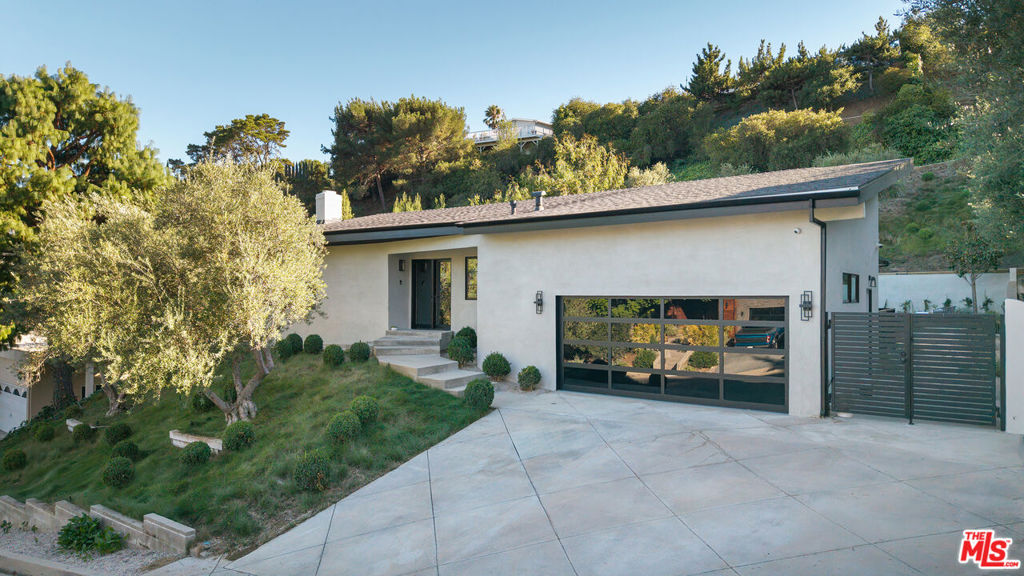 Perched in the prestigious Laurel Hills neighborhood of the Hollywood Hills, this exquisitely reimagined modern residence offers a rare blend of refined elegance and serene canyon living. This home is a curated expression of luxury living designed for discerning buyers who value privacy, style, and elevated comfort. A voluminous open-concept layout with soaring vaulted ceilings invites seamless flow between living, dining, and entertaining spaces. Every detail has been thoughtfully considered: from hand-applied Portola lime wash walls and custom built-ins to natural stone finishes and wide-plank European white oak flooring that runs throughout. Expansive picture windows flood the interiors with natural light, creating a serene indoor-outdoor connection. The home offers three generously appointed bedrooms and three spa-quality bathrooms, each crafted with a quiet elegance and bespoke materials. The primary suite is a true retreat, offering both intimacy and sophistication. Outside, the property is enveloped by mature olive trees and curated landscaping, creating a private, resort-like setting. The flat grassy yard and stunning pool provide an ideal backdrop for both quiet relaxation and stylish entertaining. The sleek smooth stucco exterior, brass detailing, and neutral color palette underscore the home's clean lines and contemporary sensibility. State-of-the-art amenities include Control4 Home Automation, Lutron lighting, and a two-car garage with EV charging. This is more than a home, it's a statement of taste and lifestyle. Tucked away in one of Los Angeles' most exclusive enclaves, this private oasis offers a rare opportunity to own a truly turnkey residence that embodies modern luxury and timeless charm.