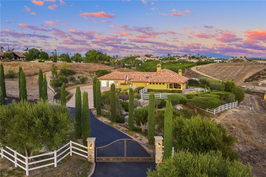 Exceptional Single-Story Wine Country Estate! Discover a truly one-of-a-kind single-story home set behind a private double-gated entrance in the heart of Temecula’s renowned wine country. Immaculate inside and out, this residence captures sweeping sunrise and sunset views across 2.74 acres of fully usable land, offering rare privacy and room to expand. Built in 2006, the home features three bedrooms and three-and-a-half bathrooms, plus an oversized three-car garage with soaring ceilings. Thoughtful upgrades include a reverse-osmosis whole-house water system, water softener, new windows, and a Generac whole-home backup generator tied directly to the electrical panel for peace of mind. The great room showcases automatic blackout blinds, a whole-house surround-sound system, and two elegant fireplaces, creating a welcoming environment for everyday living or entertaining. Outdoor amenities rival a private resort. A sparkling saltwater pool and spa overlook breathtaking sunsets, while a covered patio with a built-in barbecue kitchen and abundant seating makes entertaining effortless. A second patio features a new Alumawood cover, ideal for relaxed gatherings. The grounds boast lush, vibrant landscaping with a fully renovated sprinkler system, extensive lawn areas, and ample level space for future additions such as a vineyard, guest house, or equestrian facilities. Practical details enhance convenience and security: a newly poured asphalt driveway, a Spanish-style tile roof, and a double-gate design with automatic entry. Two recently installed air-conditioning units and a newer furnace ensure year-round comfort. Abundant RV and boat parking with hookups adds flexibility for outdoor enthusiasts. Situated in a premier section of wine country close to both the north and south wine trails, this property combines unmatched privacy with easy access to Temecula’s celebrated wineries, dining, and events. Homes of this caliber rarely come to market. With its striking location, luxurious upgrades, and endless possibilities, this estate is truly one of a kind and will not last long.