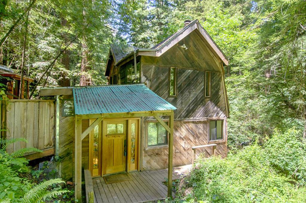 Deep in the Santa Cruz Mountains, this private retreat combines Hippie Modernism with rustic charm. It includes two detached structures: a freestanding bedroom with a loft, which has the potential to become a tiny home, and a bathhouse with advanced lighting, an oversized tub, and a shower. A flat, sunny terrace with water and a metal storage shed offer space for a large vegetable garden. A backup generator is also available. Well isolated from the neighbors in a quiet community, you'll have both privacy and the reassuring sense that there are other people in the area. The surrounding redwoods contribute to a peaceful and inspiring atmosphere. While fully livable, this home reflects the passage of time and awaits a visionary touch. Priced accordingly, it presents an opportunity to reimagine a unique forest haven where modernism meets organic living, and creativity flourishes under a redwood canopy.