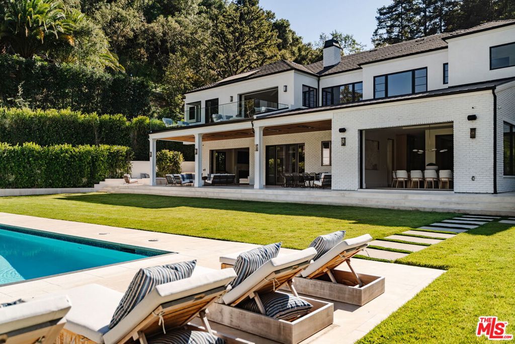 Poised behind gates on an expansive and secluded three-quarter-acre parcel, this newly completed Traditional estate is a triumph of scale, craftsmanship, and refined architectural vision. Set within one of Brentwood's most sought-after enclaves, the residence spans nearly 11,000 square feet of exquisitely tailored living space, comprising a grand main residence and a fully detached, two-story guest house -- each executed with an exacting standard of design and finish. A dramatic double-height foyer introduces interiors of quiet grandeur, where custom millwork, hand-selected natural stone, and a gallery-like flow elevate both form and function. The formal living room is anchored by a marble fireplace and sculptural wine bar, while the adjoining dining room opens entirely to the outdoors via a retractable glass wall, creating seamless flow to the estate's lush grounds. At the center of the home, a marble-clad chef's kitchen combines striking aesthetics with professional-grade performance, featuring Sub-Zero and Wolf appliances, an artisan coffee bar, and bespoke cabinetry. A sunlit breakfast area opens to a gracious family room, while a lounge and seated wet bar, dedicated office, guest suite, and two powder rooms complete the main level. An elevator and dual staircases ascend to the private quarters above, where five ensuite bedrooms are thoughtfully arranged, including an extraordinary primary retreat with soaring beamed ceilings and glass doors opening to a private terrace. Two couture-inspired dressing rooms and a spa-caliber bath, complete with a dual steam shower and sunlit soaking tub, offer a daily ritual of serenity. An upper-level screening room, wet bar, gym, and additional family room provide flexible spaces for recreation and relaxation. Outside, the resort-style grounds unfold with effortless sophistication: a sparkling pool and spa with Baja shelf and auto cover, a covered and heated entertaining pavilion, outdoor kitchen, firepit lounge, sport court, and vast emerald lawn, all surrounded by mature hedging that ensures privacy and tranquility. The two-story guest house offers unparalleled versatility, featuring a living room, kitchenette, powder room, and an upper-level bedroom suite with a private balcony, ideal for a pool house, accommodating extended stays, or a studio. Additional highlights include a fully integrated home automation system, dual laundry rooms, and a 3-car EV-ready garage accessed via a cobblestone motor court. More than a home this is a rare architectural statement, exquisitely composed and beautifully aligned with the timeless spirit of the Westside.