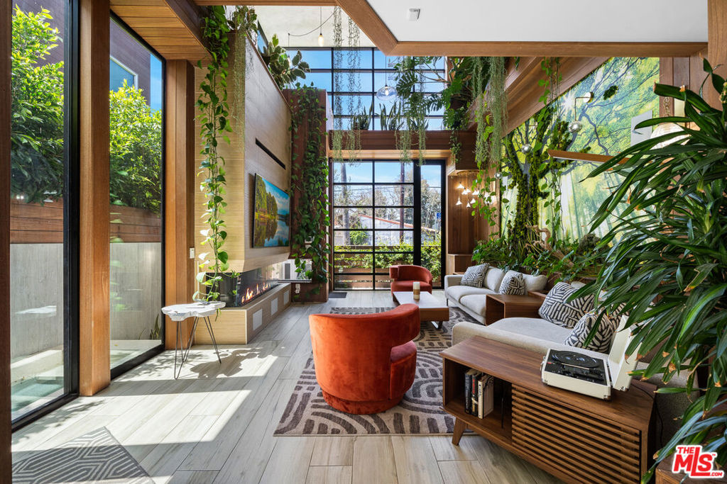 Presenting the iconic "Maya, Lady of Botanica," one of three newly built "Glass Ladies Houses" by acclaimed designer Alon Zakoot. This tropical zen Tulum-inspired trophy property, has been featured in over fifty publications globally, and is known for its harmonious blend of tropical jungle elements and botanical accents. Step into Maya's realm, where she seamlessly transports you to a world of natural beauty and tranquility. Upon arrival, prepare to be captivated by the grandeur of the towering glass-and-steel entrance, complemented by sloped overhead lines and meticulously curated drought-tolerant flora. The living room features a decadent fireplace, shimmering accent wall, and sliding glass doors that open onto the enchanting patio and walls of glass onlooking the sparkling saltwater pool and spa.The masterfully designed kitchen boasts a double-waterfall island, state-of-the-art appliances, custom cabinetry, and a convenient pass-through to sparkling saltwater pool and spa and the main-level indoor/outdoor lounge, complete with fire pit and additional bar seating. The dining room is adorned with a staircase-turned-art-piece. Ascend to the upper level, where the primary suite awaits, offering a private balcony with stunning views, a floating dual-sink vanity, rainwater shower, separate tub, and a brilliant clerestory window framing vistas of mature palms. The additional bedrooms and bathrooms showcase the finest fixtures and finishes, ensuring a luxurious living experience. Upstairs awaits a stunning rooftop deck with an outdoor kitchen, dining area, lounge furniture and oversized firepit. The rooftop features breathtaking 360-degree views of the cityscape, mountains, downtown Los Angeles and beyond. Descend to the lower level, where a junior primary suite awaits, featuring its own fireplace and an exceptional outdoor living room adorned with a botanical wall and open-air elegance. On this level you will also find a beautiful theater, equipped with a built-in mini bar and blackout shades, as well as an atrium letting in natural elements and light, and an additional guest suite. Maya, Lady of Botanica stands as an extraordinary architectural feat, presenting a rare opportunity to own a slice of tropical Tulum paradise in Silicon Beach. Conveniently located blocks from the best shopping, nightlife and entertainment Venice has to offer on Abbott Kinney and Rose Ave, and moments from the beach, this residence epitomizes a seamless blend of luxury living and Venice lifestyle.