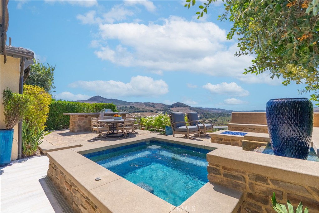 Welcome to one of Rancho Mission Viejo’s most remarkable view homes! An architectural masterpiece in the exclusive Ventana enclave in the award-winning community in Rancho Mission Viejo. This residence is designed for both grand entertaining and everyday luxury. The backyard is a private retreat featuring a custom-designed jacuzzi with a rare standing zone for a full-body hydro massage, a tranquil waterfall feature, gas fire pit, built-in BBQ with full appliances, and generous gathering space. All set against sweeping views and refreshing ocean breezes. The great room impresses with a 16-foot sliding glass door that seamlessly connects to the covered California Room, complete with fireplace, designer ceiling paneling, and a motorized retractable awning extending 16 feet for instant shade at the touch of a button. Inside, the kitchen is a chef’s dream, a built-in refrigerator, wine refrigerator, abundant cabinetry, and an oversized island invite both creativity and connection. The main level includes a full bedroom and bath, while upstairs offers a spacious loft and three additional bedrooms. The primary suite is a true sanctuary with panoramic views and a private balcony adorned with custom ceiling paneling. Additional premier features include epoxy-coated garage flooring with built-in cabinets, plantation shutters, custom closets, surround sound, and thoughtfully designed built-ins throughout. This home delivers the perfect balance of architectural design, modern comfort, and resort-style living, a rare find in one of Rancho Mission Viejo’s most coveted enclaves. Exclusive to Rancho Mission Viejo residents are all amenities in the Villages of Sendero, Esencia, Rienda and future Villages. There are community amenities for all from breath-taking resort-style pools and spas, Esencia school K-8, community farms, fitness centers, guest house, putting green, bocce ball courts, tennis and pickle ball courts, playgrounds, coffee shop, fire pits, an arcade and so much more!