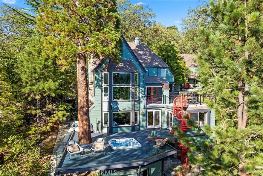 Upon entering this magnificent Lakefront home that blends a modern style with vintage appeal, you’ll look out to glistening North Bay views from massive windows.  Originally built in 1922 by James Gamble of Procter & Gamble, one of Lake Arrowhead’s visionaries, this North Shore estate spans a gently terraced half-acre with full-day sun and spectacular sunsets. Expanded, updated, and lovingly maintained over decades, this home marries timeless elegance with contemporary comforts.  The floor plan offers multiple indoor/outdoor areas, 5 bed-rooms including a spa-like primary suite and a separate guest cottage suite, four baths, a two-car garage and a single slip dock with a double-sized granite pier.

The heart of the home is the spectacular two-story great room, where exposed beams and a floor-to-ceiling granite wood-burning fireplace create an ambiance of warmth yet grandeur. A long window seat invites you to lounge with a book, sip a glass of wine, or simply take in the ever-changing hues of the sparkling lake below.  The bright kitchen is outfitted with top-of-the-line Viking appliances. The double french doored dining area opens onto a sprawling entertaining deck, commercial-grade Viking grill, refrigerator, and bar—perfect for al fresco summer gatherings.  Also on the main level is a versatile bedroom and bath which could be an office, den or study. It looks out to a soothing recirculating stream water feature.

Below a spacious family room, with warm wood paneling and cabinetry, window seating, a built-in bar, big-screen TV, french doors open to another expansive Trex deck built around a majestic 100-year-old incense cedar. Here you’ll find a new inlaid hot tub/spa, along with space for sunbathing or enjoying a competitive game of ping-pong.  A frameless glass railing ensures unobstructed views.  Additional updates include dual-pane Andersen windows, a DaVinci composite slate roof, hardwood flooring, a whole-house generator, new HVAC and SONOS speaker systems,  a beautiful 1k bottle wine cellar, and a private gym.  Granite pathways lead from a mature rose garden and fruit trees to the private pier and dock below fully equipped with Bbq, refrigerator, seating. This rare and iconic North Shore original offers a unique opportunity to own a piece of Lake Arrowhead’s history. With decades of thoughtful care and upgrades that enhance its authentic character, this home is listed at $4,499,000. Furnishings are negotiable per seller’s inventory.