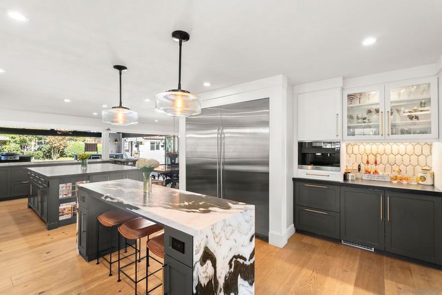 NEW FLOORS! Welcome to one of Poway’s most distinguished estates, quietly set at the end of a cul-de-sac in the prestigious gated community of The Grove. Blending timeless design with exceptional craftsmanship, this residence offers more than 5,300 sq. ft. of elegant living with 4 bedrooms plus an office / den, grand vaulted ceilings, French doors, custom millwork, and light-filled living spaces. The gourmet kitchen is designed for everyday luxury with custom cabinetry, a spacious center island, premium appliances, ice machine, built-in espresso machine, wine fridge, pot filler, and walk-in pantry. Formal living and dining rooms feature a marble fireplace and crown molding, while the family room offers built-ins and views of the resort-style backyard. The primary suite includes dual walk-in closets and a spa-inspired bath with soaking tub and oversized shower. Outdoors, enjoy a true Southern California retreat with a PebbleTec pool & spa with slide and waterfall, pool bathroom, outdoor shower, and a fully equipped outdoor kitchen with bar seating, beverage fridges, ice maker, grill station, and sink. A lighted tennis/basketball court, batting area, play space, garden beds, fruit trees, and RV/boat parking complete the grounds. Additional highlights include owned solar and a private irrigation well. A detached guest house offers a living room, kitchen, bedroom, and laundry, ideal for guests or multigenerational living. Located across from Poway High in a private, gated enclave, this estate delivers luxury, convenience, and a rare lifestyle opportunity.