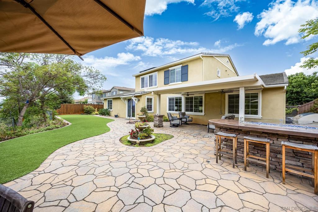 This stunning Sky Ranch dream home is part of the prestigious Eagle Pointe development. It has everything you could ask for in a luxury home: paid-in-full solar, a low-maintenance turf yard with a BBQ island, a three-car garage with an EV charger, a water filtration system, a chef's kitchen featuring high-end appliances with double ovens, and a custom-built-in fridge. The floor plan features a formal dining room with a butler's pantry, a play area/office adjacent to the family room, two bedrooms with en-suite bathrooms downstairs, two fireplaces, and a spacious primary suite with a walk-in closet, double sinks, and a separate tub and shower. The tranquil backyard offers privacy and views of the mountains and El Cajon Valley!