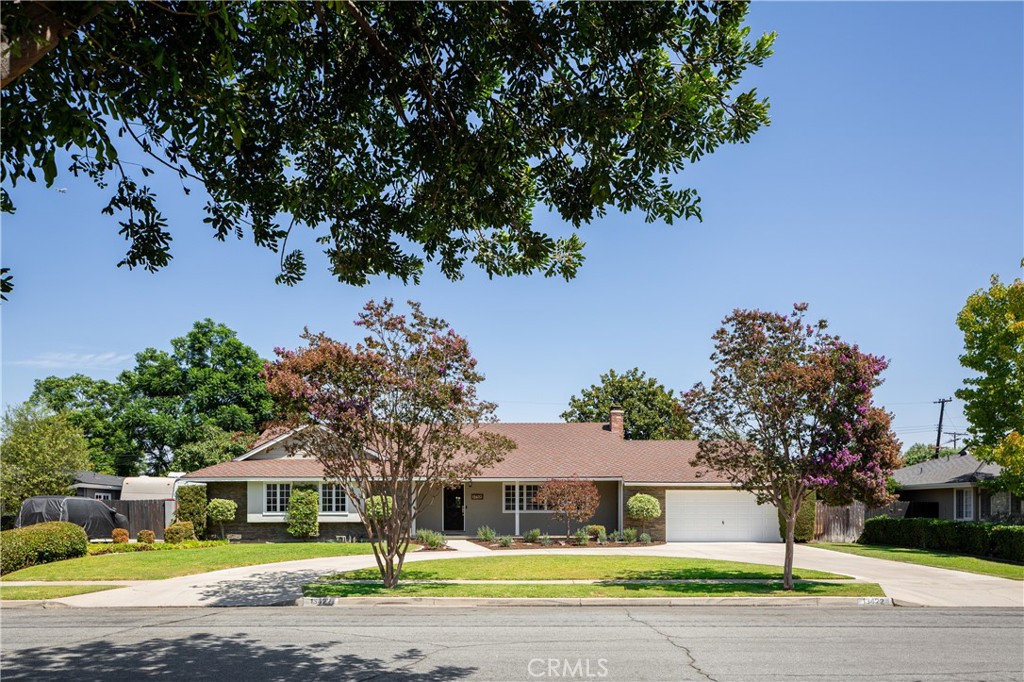 Welcome to this charming single-story ranch home, situated on one of North Tustin’s premier streets, surrounded by large lots and pride of ownership throughout the neighborhood. A half-circle driveway, covered front porch, and attached two-car garage create a welcoming entry. Inside, the spacious family room features a fireplace and expansive windows overlooking the front yard. At the heart of the home, the dining room offers a second fireplace and opens seamlessly to the remodeled kitchen with wood cabinetry, marble countertops, stainless steel appliances, and a sink overlooking the backyard. Just beyond, a versatile living room at the rear provides flexible space for a playroom, office, gym, or lounge. The bedroom wing includes two secondary bedrooms at the front of the home, which share a full bathroom with dual sinks and a bathtub. The primary suite is tucked at the back, complete with French doors to the backyard, an en suite bath, and a walk-in closet. Additional highlights include a freshly painted interior, dual-pane windows, an updated roof, hardwood flooring throughout, and a laundry room with a convenient half bath. Mature landscaping enhances the expansive lot, creating a private setting with plenty of room to enjoy. Located within the sought-after Tustin Unified School District and served by Foothill High School, this home also offers excellent access to the 55, 22, and 5 freeways, making for an easy commute across Orange County.