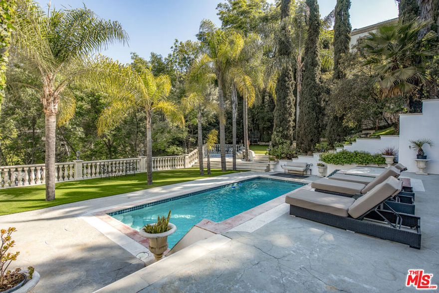 Gated Mediterranean estate nestled at the end of a quiet cul-de-sac in the heart of the Hollywood Hills. Privately set on nearly an acre, this custom-built oasis offers 5 bedrooms and 6 baths with over 5,000 sq ft designed for grand-scale entertaining. A dramatic motor court, lush grounds, and sweeping views set the tone for this resort-style retreat, featuring a showstopping pool and spa, a white Italian gazebo, and a waterfall. Inside, the home boasts soaring ceilings, maple floors, and a chef's dream kitchen with a large breakfast area, formal dining, and sun-drenched living and family rooms divided by a dual fireplace and full bar. The lower level is dedicated to luxury living, with a lavish primary suite offering a fireplace, private balcony, spa bath, and massive walk-in wardrobe. Two oversized guest suites open directly to the pool, while a separate office/library wing and maid's quarters offer added versatility. Complete with a 3-car garage, sauna, and even a helicopter pad (per owner), all just minutes from Universal Studios and the best of LA. AVAILABLE FURNISHED OR UNFURNISHED. Available for short or long-term rental.