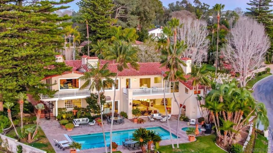 La Jolla’s most storied Muirlands Estates home offers panoramic ocean views and timeless design. Revered for its rich history and lux offerings, the prominent home is set on an exquisitely manicured 38,227-sf corner lot fronted by towering pines. Beyond the scrolled gates and circular drive, lies a private courtyard with stone fountain and antique doors. The stunning Edgar Ulrich-designed estate offers reclaimed wood floors, an exceptional Wolf-appointed kitchen, and sport-filled, landscaped yards to meet all of your needs. From meticulous glass-blown chandeliers and hand-plastered hearths to welcoming koi pond and basketball court, the home deftly integrates enduring design with contemporary amenities.  The property features superb interior and exterior spaces and design. A grand entry foyer offers a stunning curved wrought-iron staircase. Most of the 8 bedrooms are ensuite. Other interior room highlights include a library, fitness room, large playroom, gallery and niche spaces, two second-floor gallerias, private view deck off the primary suite, 7 baths and 3 half-baths, housekeeper suite, guest suite, and 4-car garage. French doors and large windows offer seamless indoor/outdoor transitions and endless views. A private staircase connects ancillary bedrooms to the kitchen/family room area. Exterior spaces, with fabulous ocean views, are surrounded by well-manicured and lush landscaping and include a pool, spa, basketball court, and putting green.