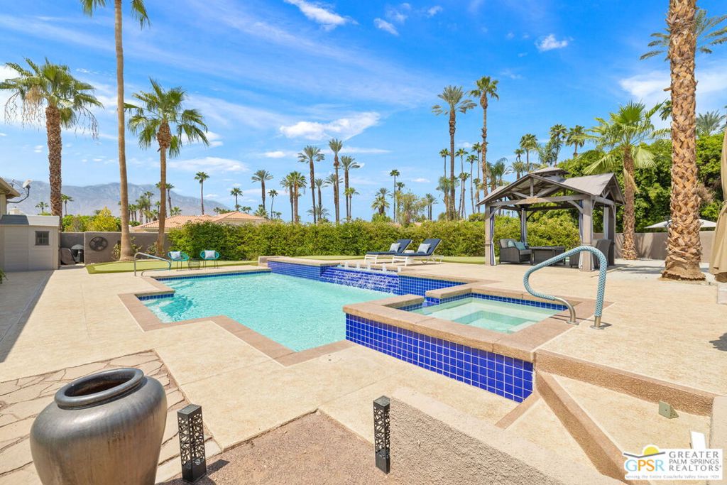Big, Wide-Open Views at Tamarisk! Panoramic mountains, Rancho Mirage's swaying palms, and outdoor living as pretty as you'll find set this home apart. Three ensuite bedrooms, a three-car garage, and more than one-third acre combine with OWNED SOLAR to deliver an exceptional desert retreat. Double doors open to an impressive foyer that flows into formal living and dining spaces with fireplace, all under tall ceilings that define the home. The family room with wet bar and wine storage looks directly onto the pool, while the kitchen is centered by a generous island with abundant storage and an adjacent breakfast area. Outdoor dining is just steps away. The wrap-around covered patio overlooks a sensational pool finished in blue tile with cascading waterfalls, a spa, and an elevated deck with chaise lounges designed to take in the views. A putting green, outdoor shower, expansive lawn, and gazebo add to the resort-style atmosphere, all within a walled and private setting. The primary retreat sits behind double doors and is substantial in scale, offering sliders to the outside, a corner fireplace, large walk-in closet, spa tub, tiled shower, and dual vanities. Guest Bedroom Two includes a walk-in closet and access to the side patio, while Guest Bedroom Three also opens outside. A central hall lined with built-ins, a utility room, and an additional bath with walk-in shower complete the interior. Take the Matterport Virtual Tour for a better sense of it all!