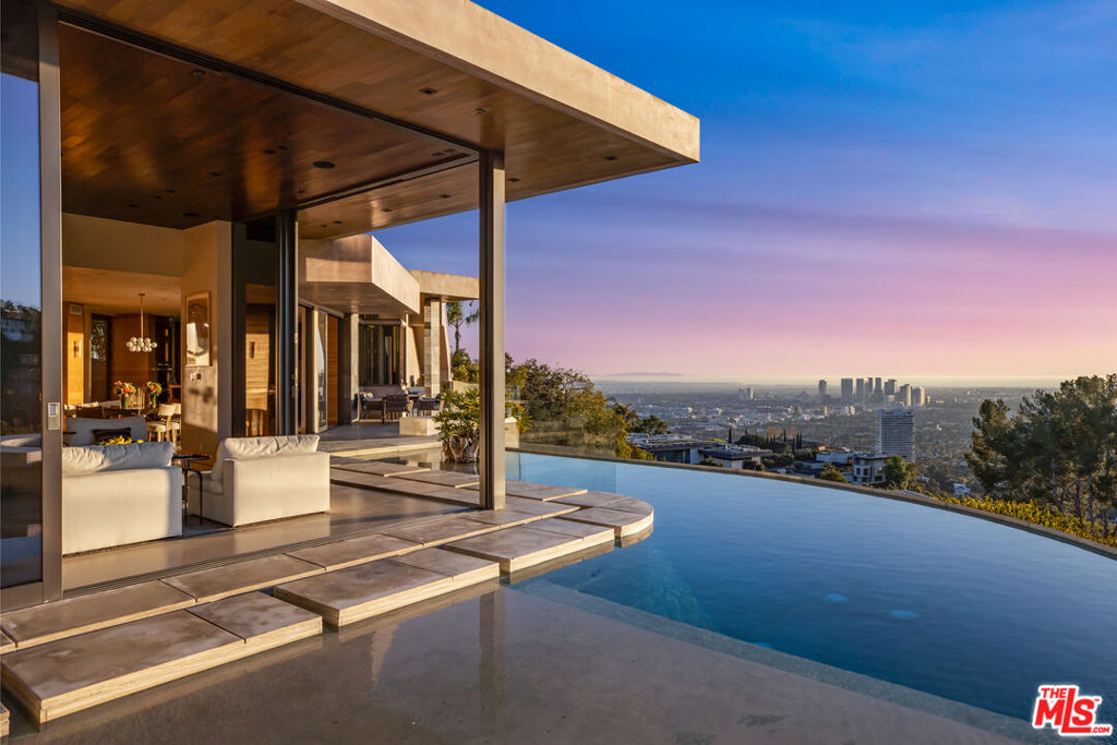 This home dissolves the boundary between earth and sky, its glass-wrapped rooms frame sunrise, sunset, and every shifting light beyond as integral elements of its design. Every room is encased in glass walls that slide open to multiple patios and balconies, immersing indoor spaces in light, air, and unrivaled views. With soaring ceilings and expansive volumes, the home is perfectly tailored for grand entertaining, its open layout fostering effortless flow from one space to the next. Crafted for a full sensory experience, the property incorporates cutting-edge technology and premium materials throughout. Thoughtful design ensures that beauty and function coexist, creating a living environment that is both visually compelling and deeply welcoming.