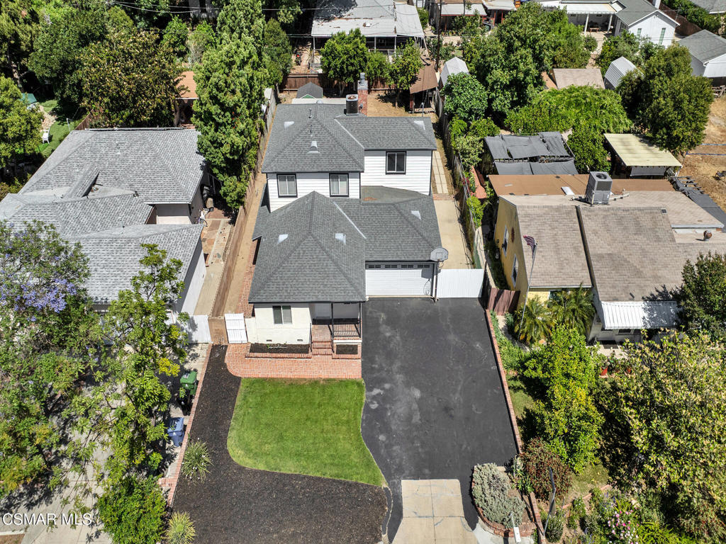 Versatile living with room to grow in the heart of Winnetka! This spacious and multi-functional two-story home offers 2,115 sq. ft. of living space on an 8,109 sq. ft. lot and features an adaptable 3 bedrooms, 2 bathroom layout with thoughtful upgrades throughout. Inside, you'll find fresh interior paint, new wood-like tile flooring, and a welcoming living room that flows into a granite-appointed kitchen with maple cabinets, stainless GE appliances, and an adjacent dining area. A glass door leads to the side yard, creating an easy indoor-outdoor connection. The main level includes two comfortable bedrooms with mirrored closet doors, one with direct access to the backyard, along with a full granite bathroom featuring a tub/shower combo. The spacious laundry room includes built-in upper cabinets, a desk area, and a storage closet, with additional storage tucked beneath the staircase. A carpeted spiral staircase leads to the upper level, which exclusively envelopes the primary suite--offering privacy and space all its own. This retreat features a two-room configuration, with one area showcasing a marble raised hearth fireplace with storage and sliding doors to a private balcony looking over the tree-lined backyard, and the second space--separated by French doors--ideal for a home office, den, or sitting area. The suite also includes a generous walk-in closet with built-in drawers, shelving, and a desk, along with an en suite bathroom offering a dual-sink vanity and an oversized tiled shower. The backyard offers a play area with a swing set, a firepit, a brick patio with an overhead cover from the balcony above, and a brick walkway along one side yard and a paved, gated RV access area (approx. 10' x 40') on the other side, along with an extra-large asphalt driveway featuring a built-in basketball hoop in the front. The detached finished one-car garage with tile flooring is ideal as a home gym, studio, or workshop and connects to a two-car garage with storage cabinets and both have roll-up doors. Set in an established and desirable neighborhood, this home is just minutes from Westfield Topanga, The Village, CSUN, Pierce College, local hospitals, and a variety of shopping and dining options. Commuters will appreciate the easy access to the 101 and 118 Freeways and the Orange Line Transit Corridor. With so much to offer inside and out, this home is a rare find in a prime Winnetka location.